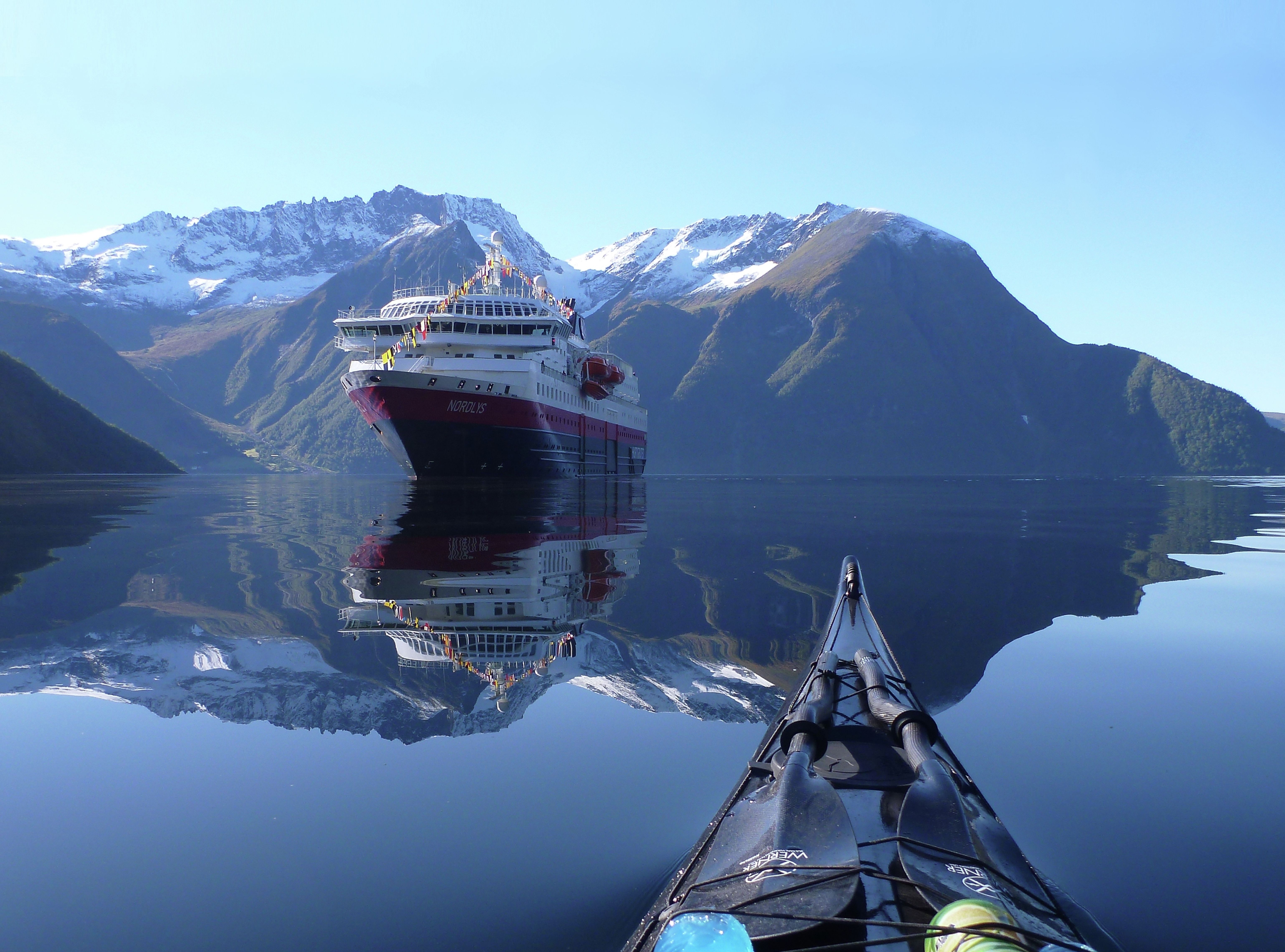 Vista del barco Hurtigruten 'MS Nordlys' desde un kayak en el fiordo Hjørundfjord, en la Noruega de los fiordos.