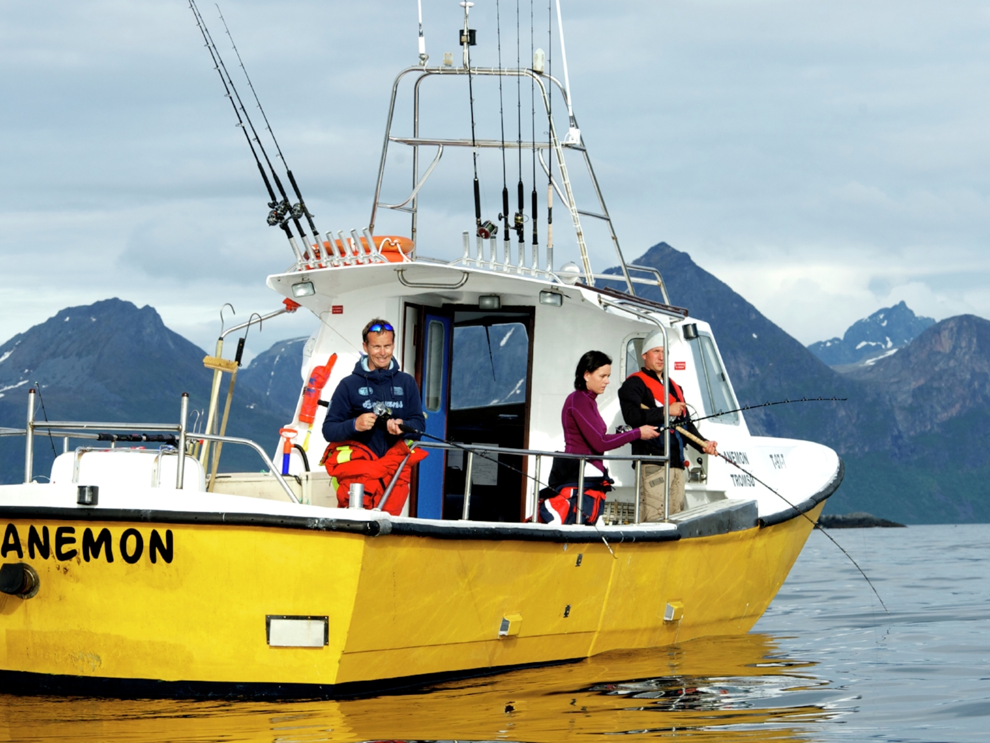Three people sea fishing from a fishing boat at Kattfjorden in Northern Norway