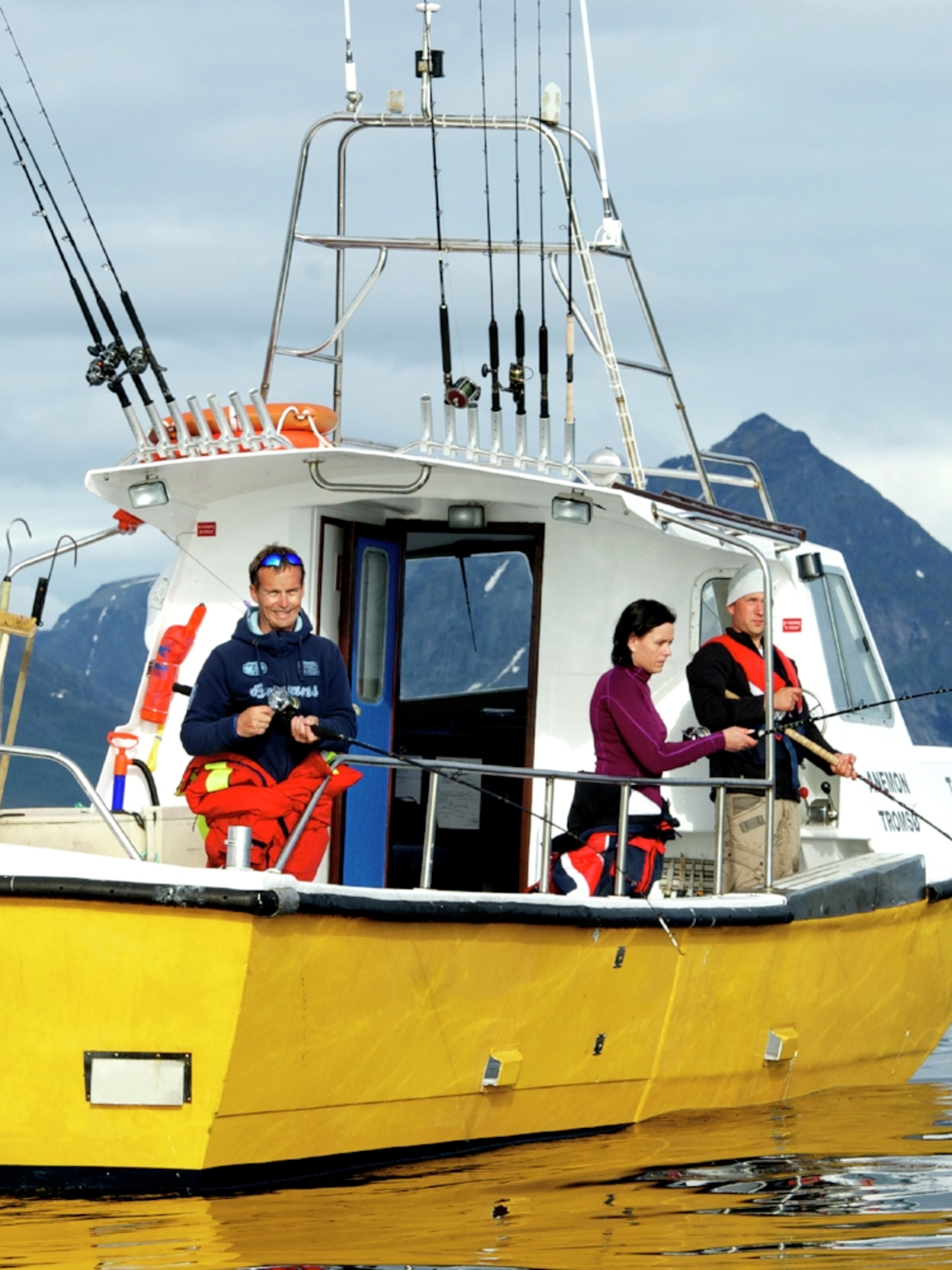 Three people sea fishing from a fishing boat at Kattfjorden in Northern Norway