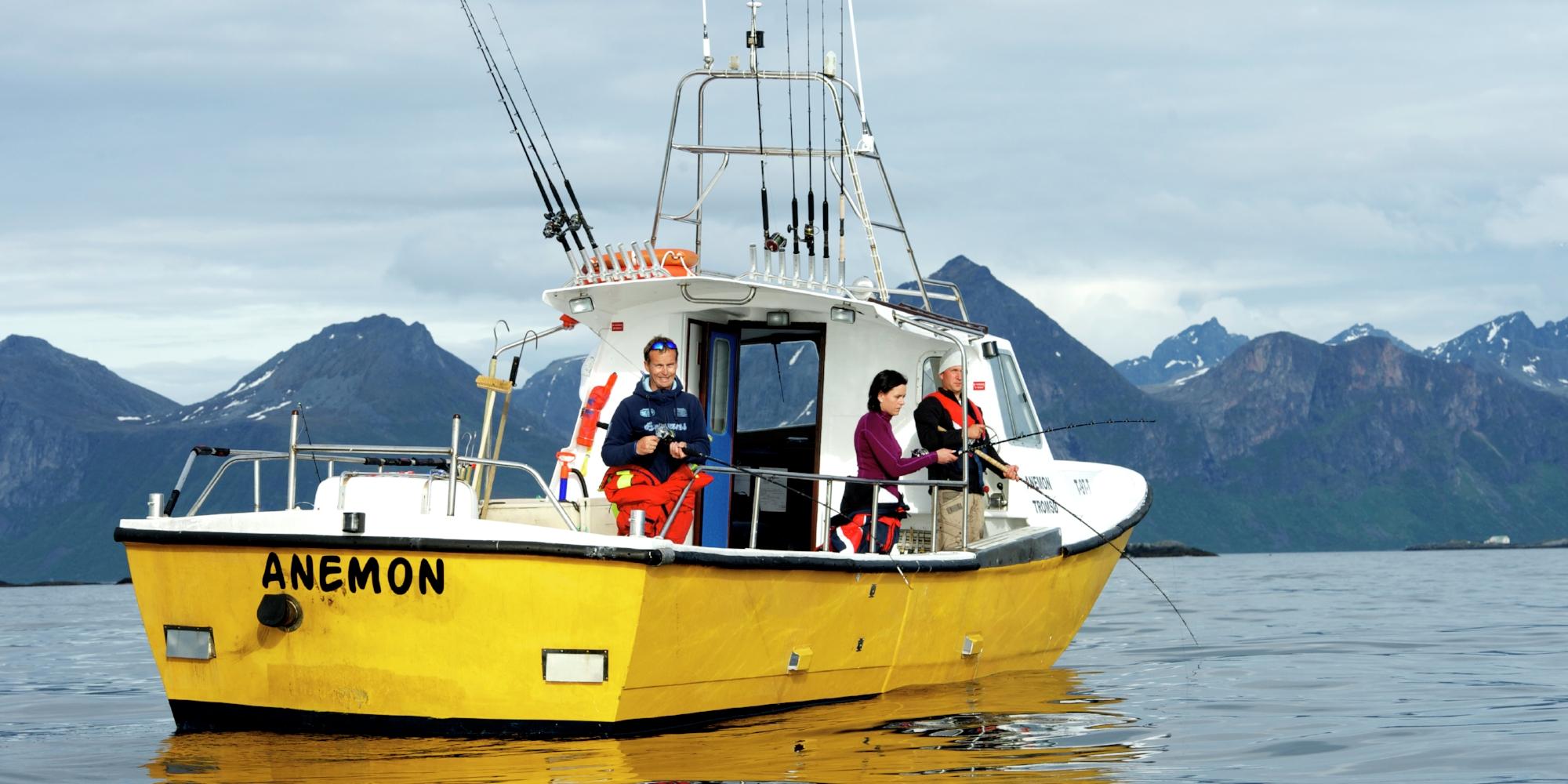 Three people sea fishing from a fishing boat at Kattfjorden in Northern Norway