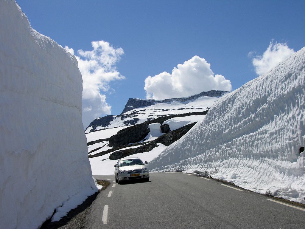 Car driving between tall walls of snow along the road