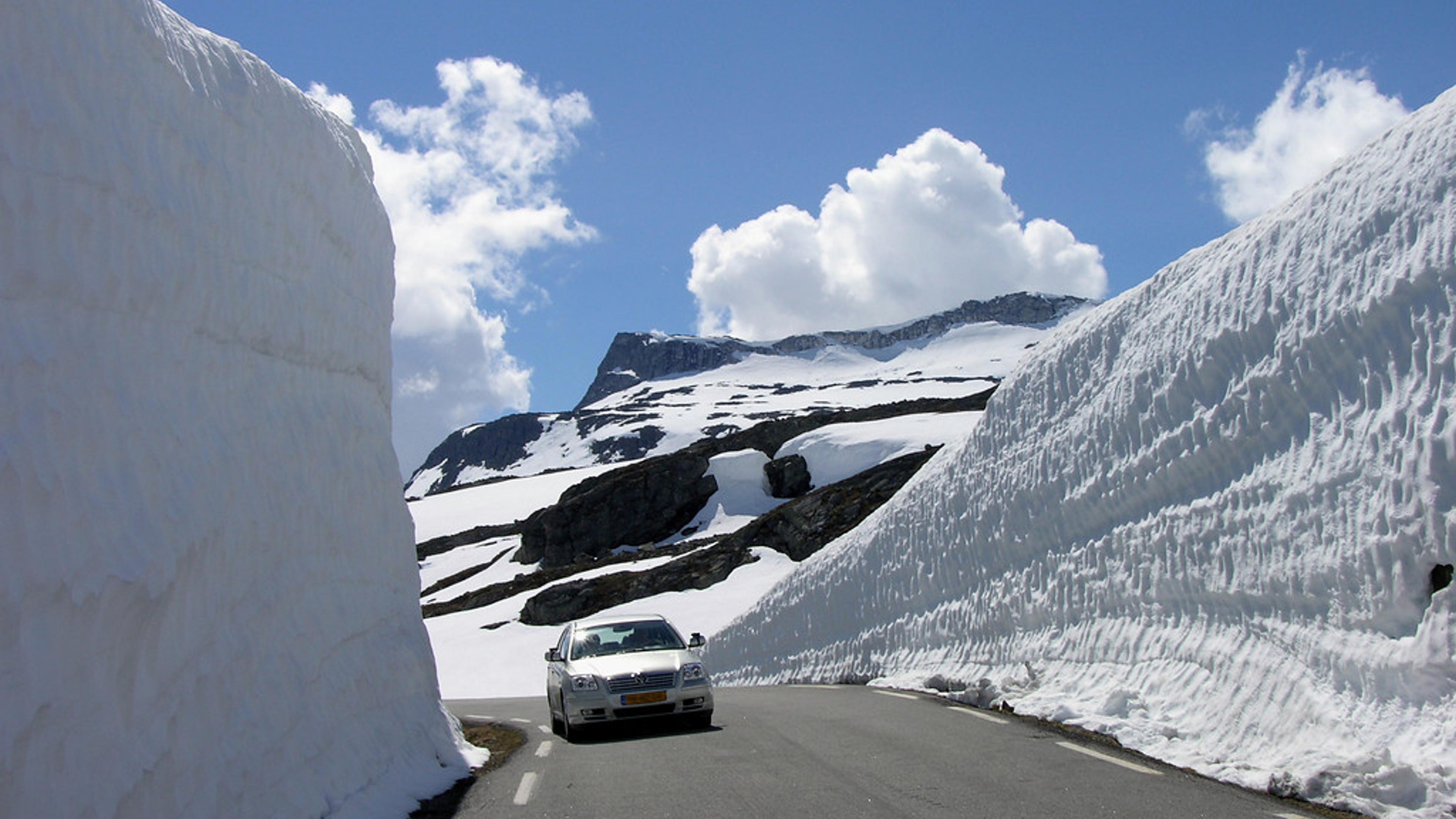 Car driving between tall walls of snow along the road