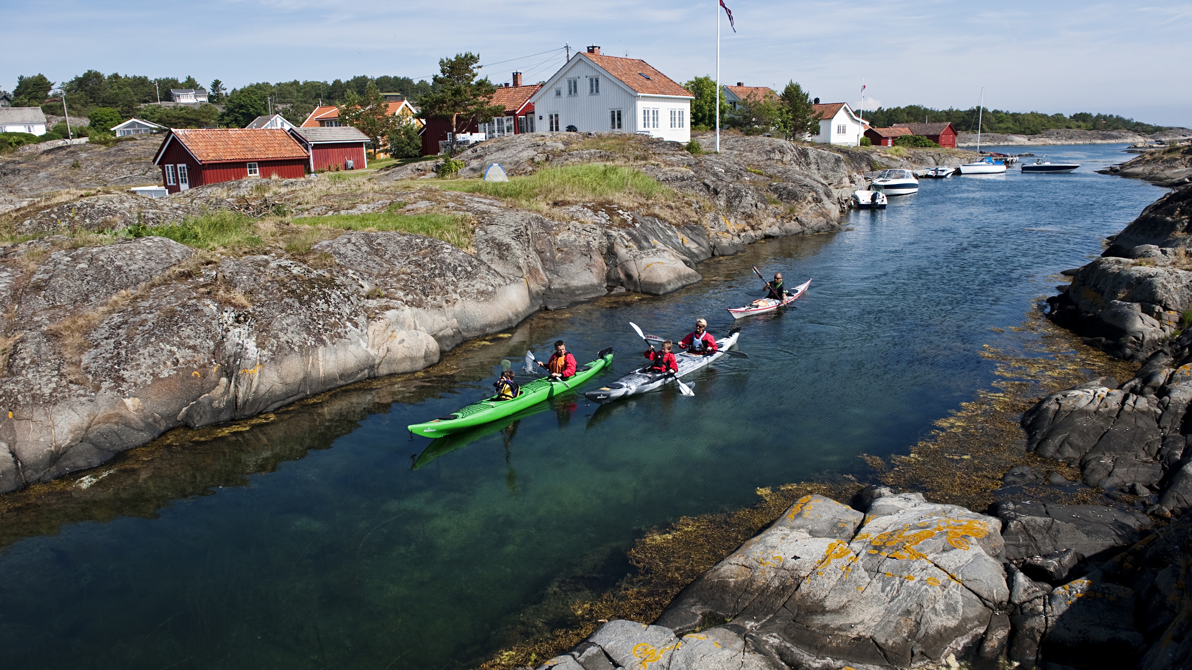 A family kayaking through a strait in the archipelago of Risør, Southern Norway