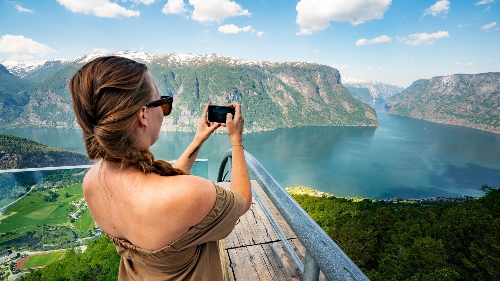 Woman taking a picture of the beautiful Aurlandsfjord in Fjord Norway