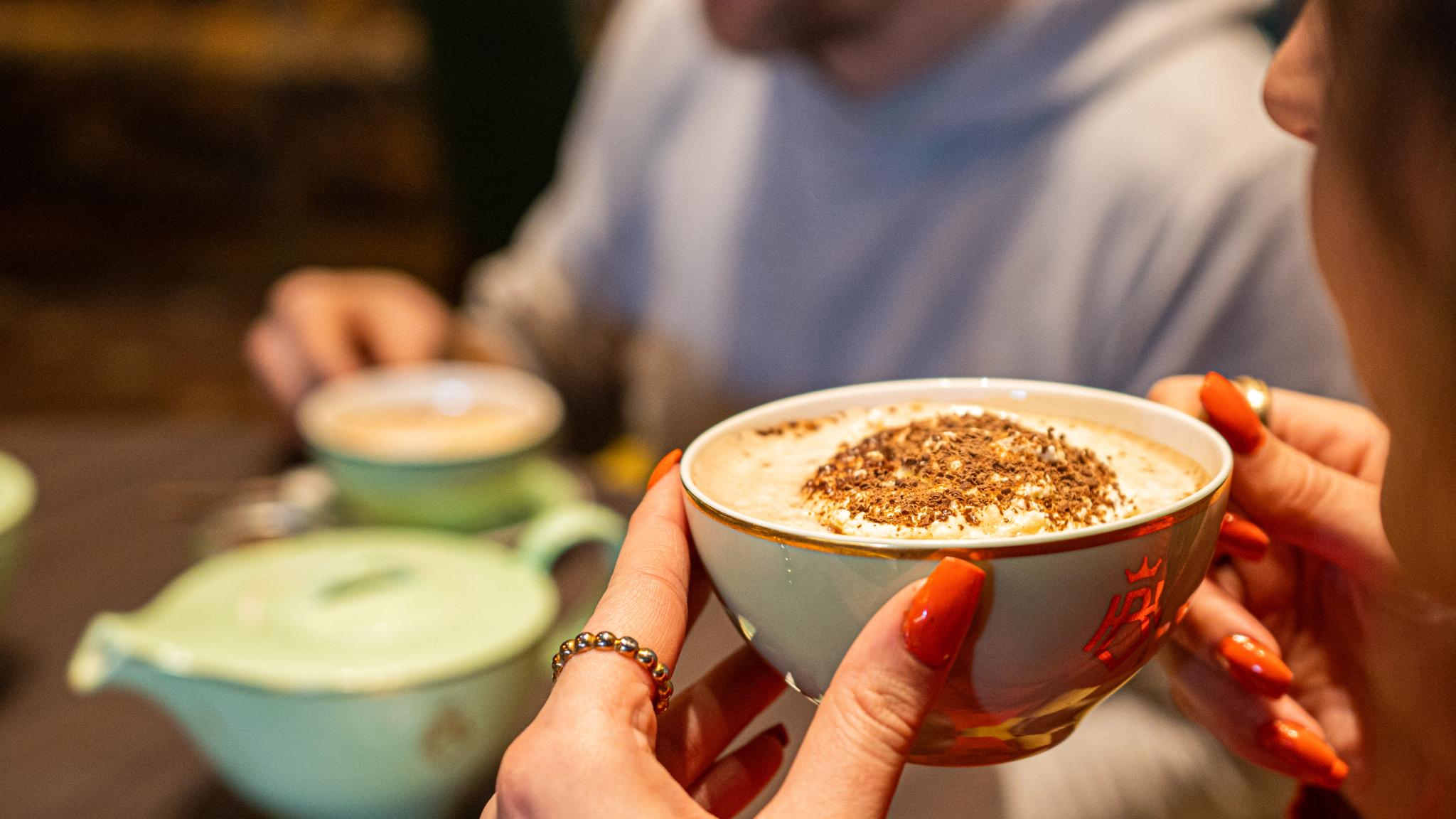 A hand is holding a hot chocolate with cream.