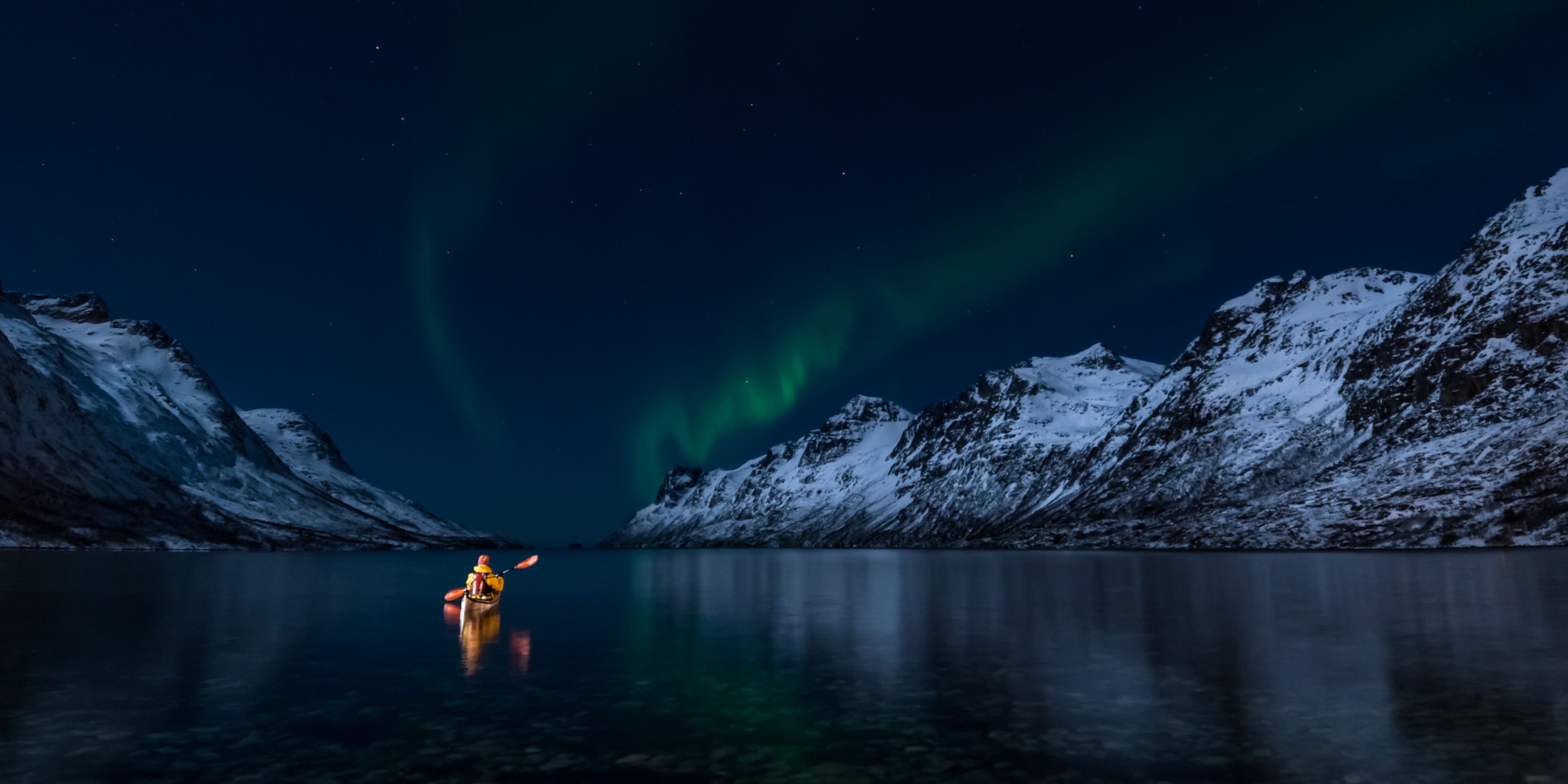 A woman paddling under the northern lights in Lofoten, Northern Norway