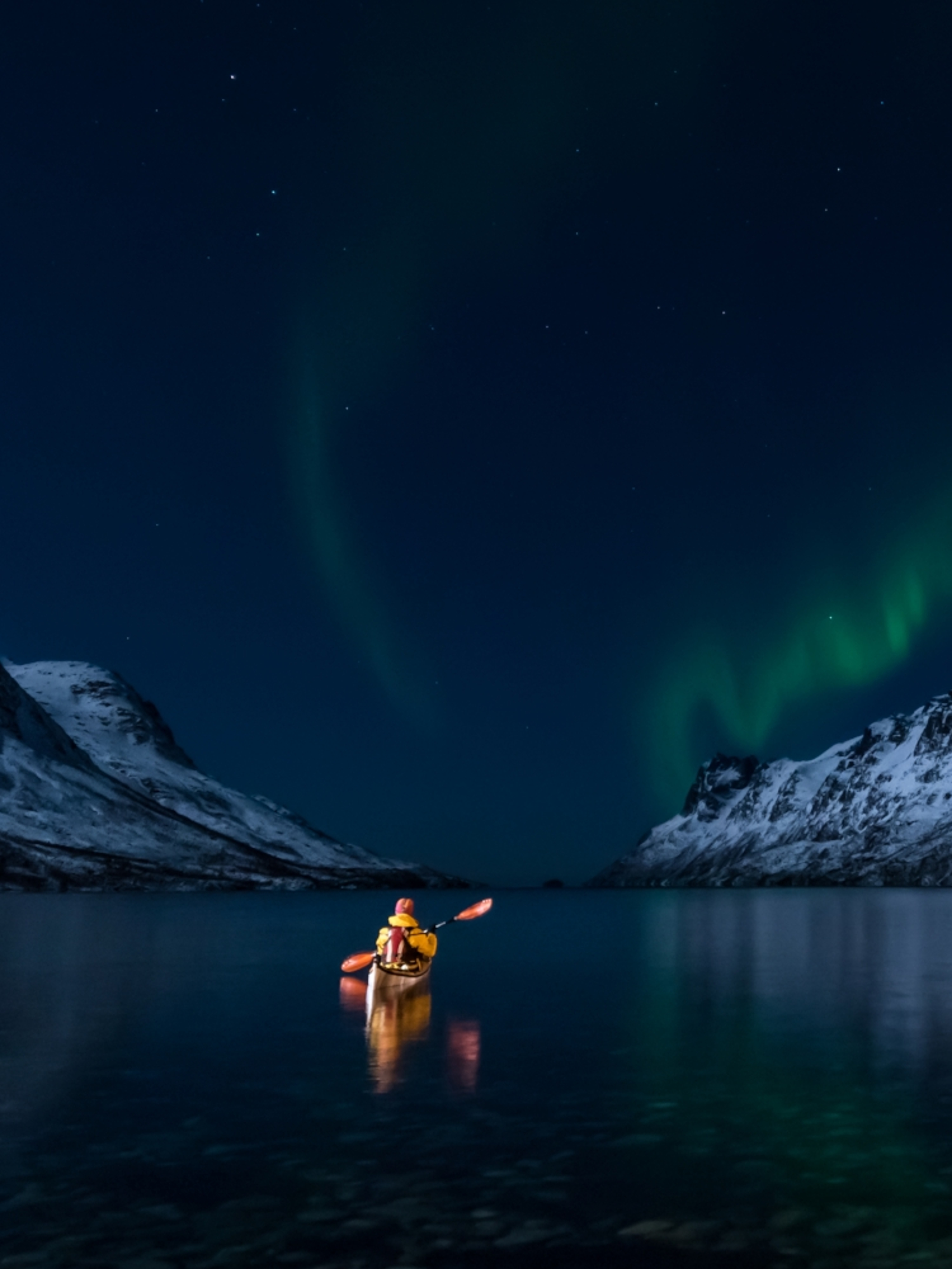 A woman paddling under the northern lights in Lofoten, Northern Norway