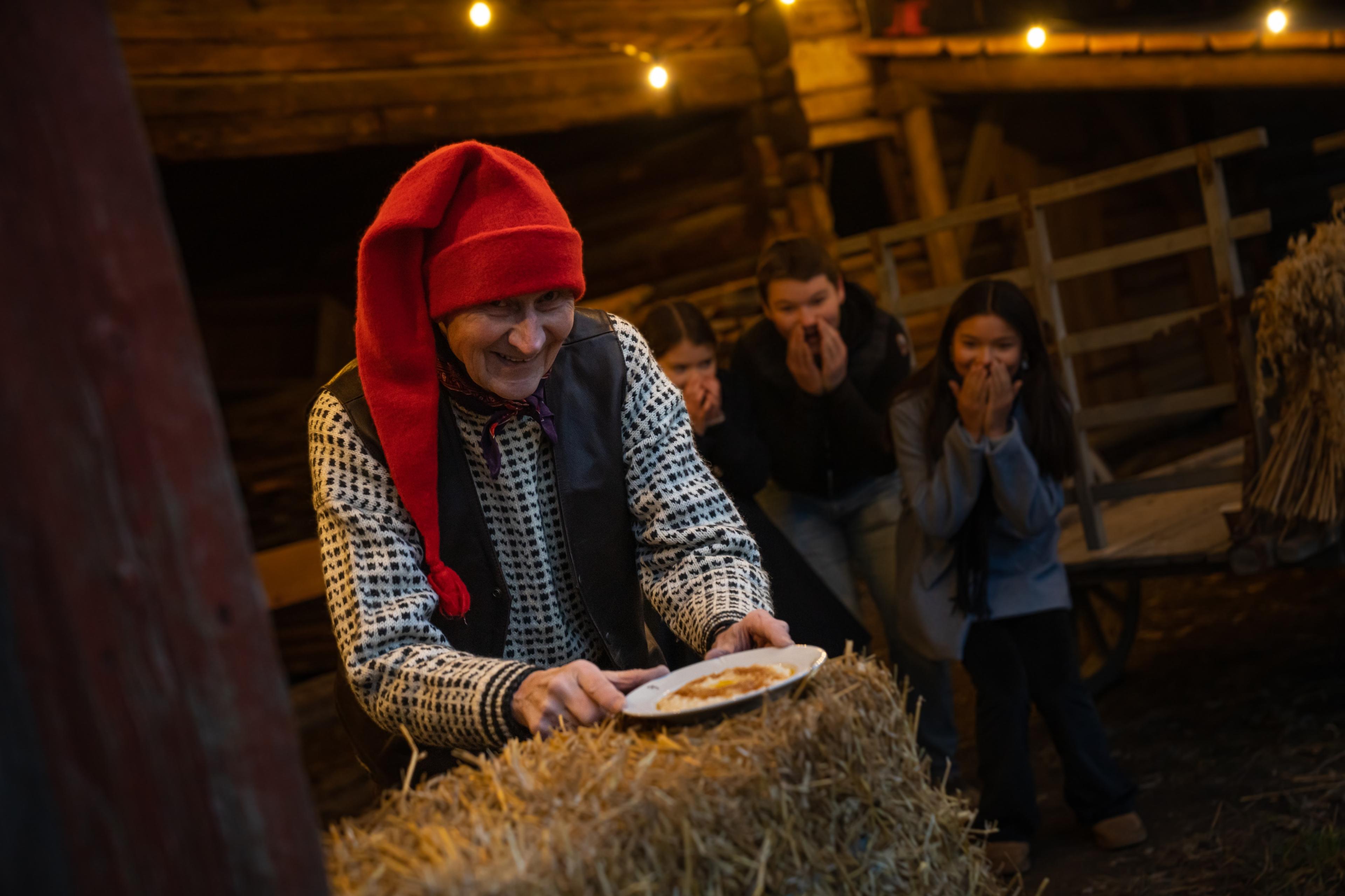 The Norwegian Santa is getting a hold of the porridge, while children is excited in the background at Bygdøy, Eastern Norway