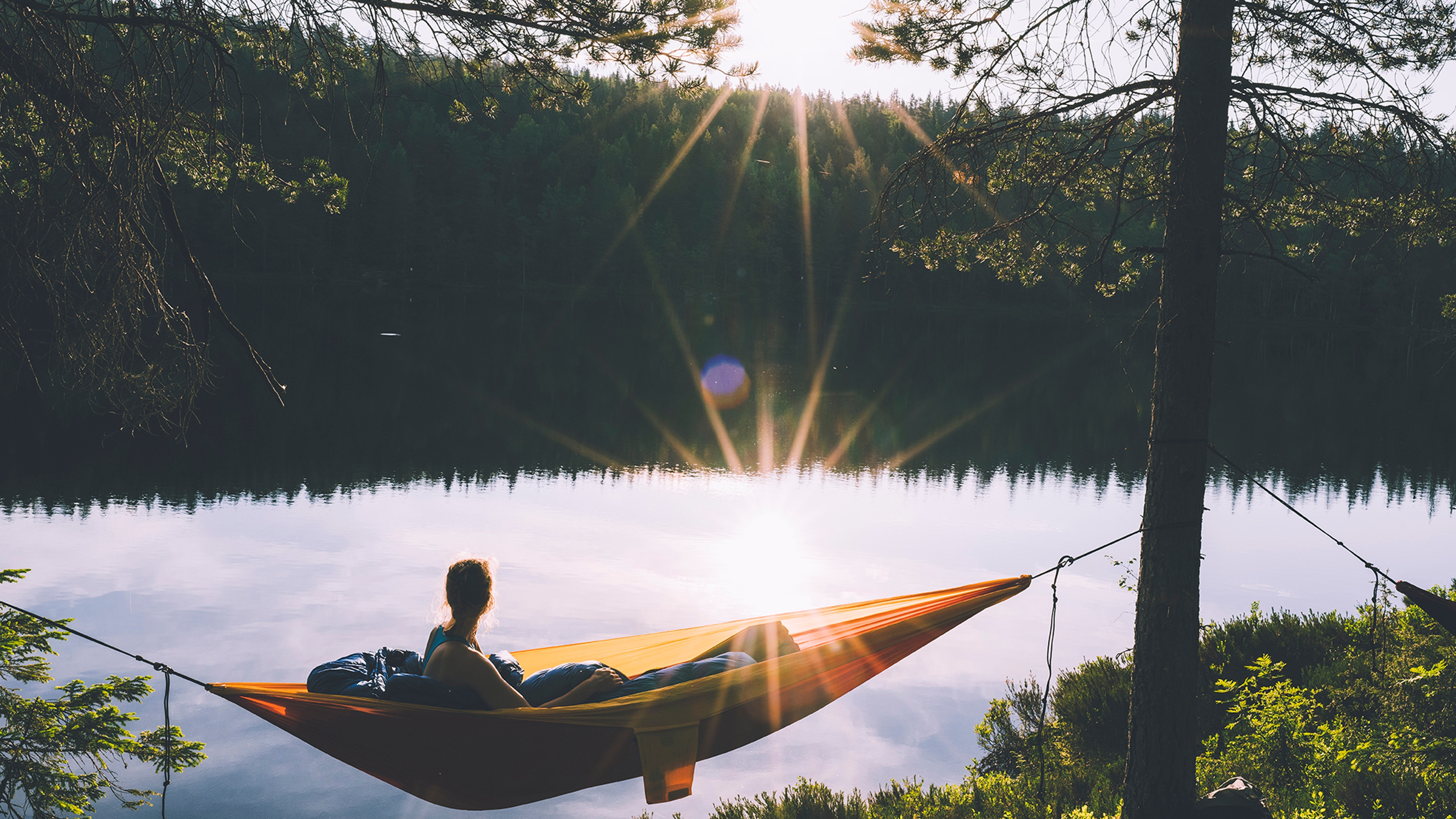 Woman in hammock at sunset in the Nordmarka forest in Oslo, Eastern Norway