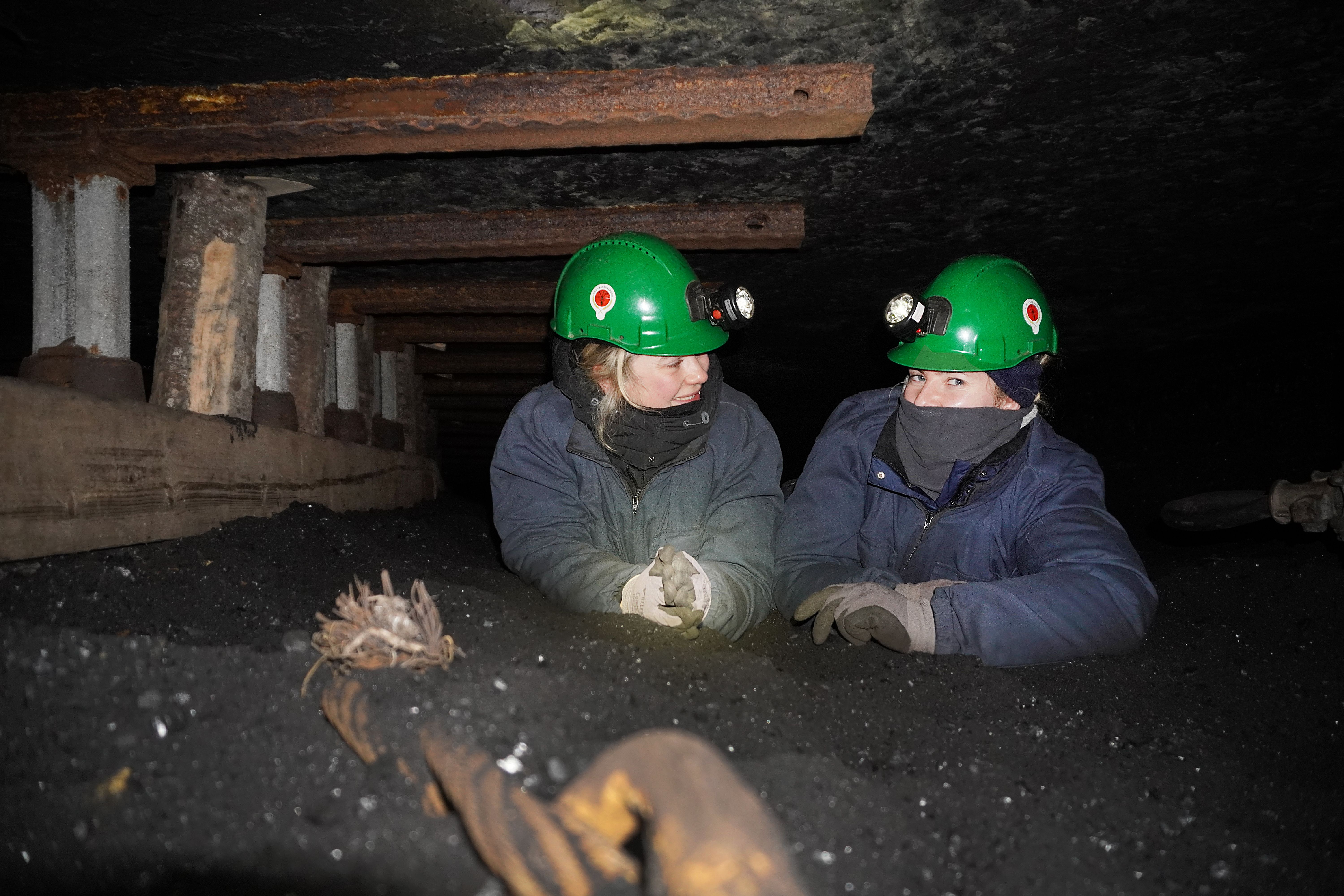 Two women in mining clothes in a coal mine