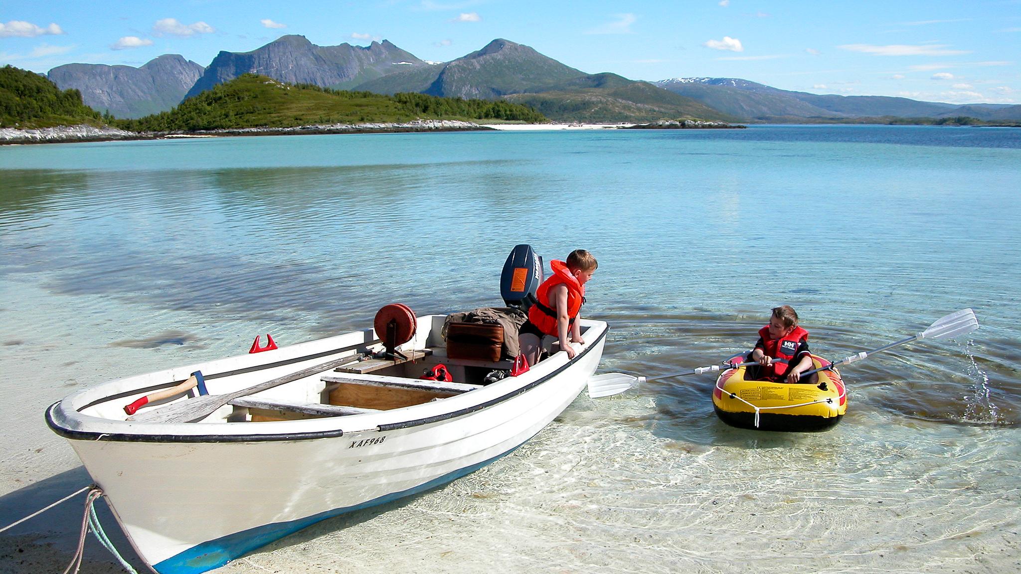 Two kids in boats by the beach in Bergsøyan in Senja, Northern Norway