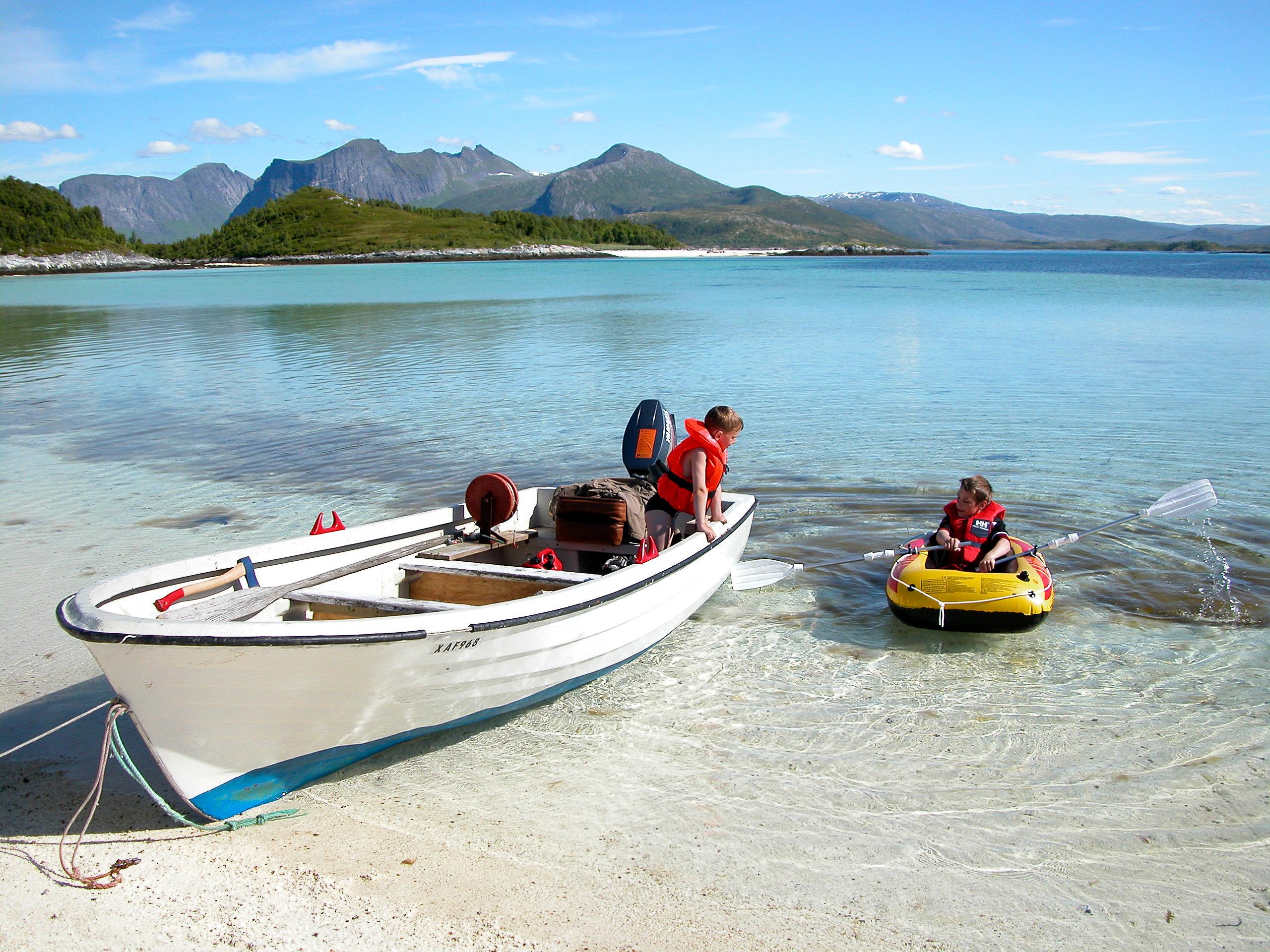 Two kids in boats by the beach in Bergsøyan in Senja, Northern Norway