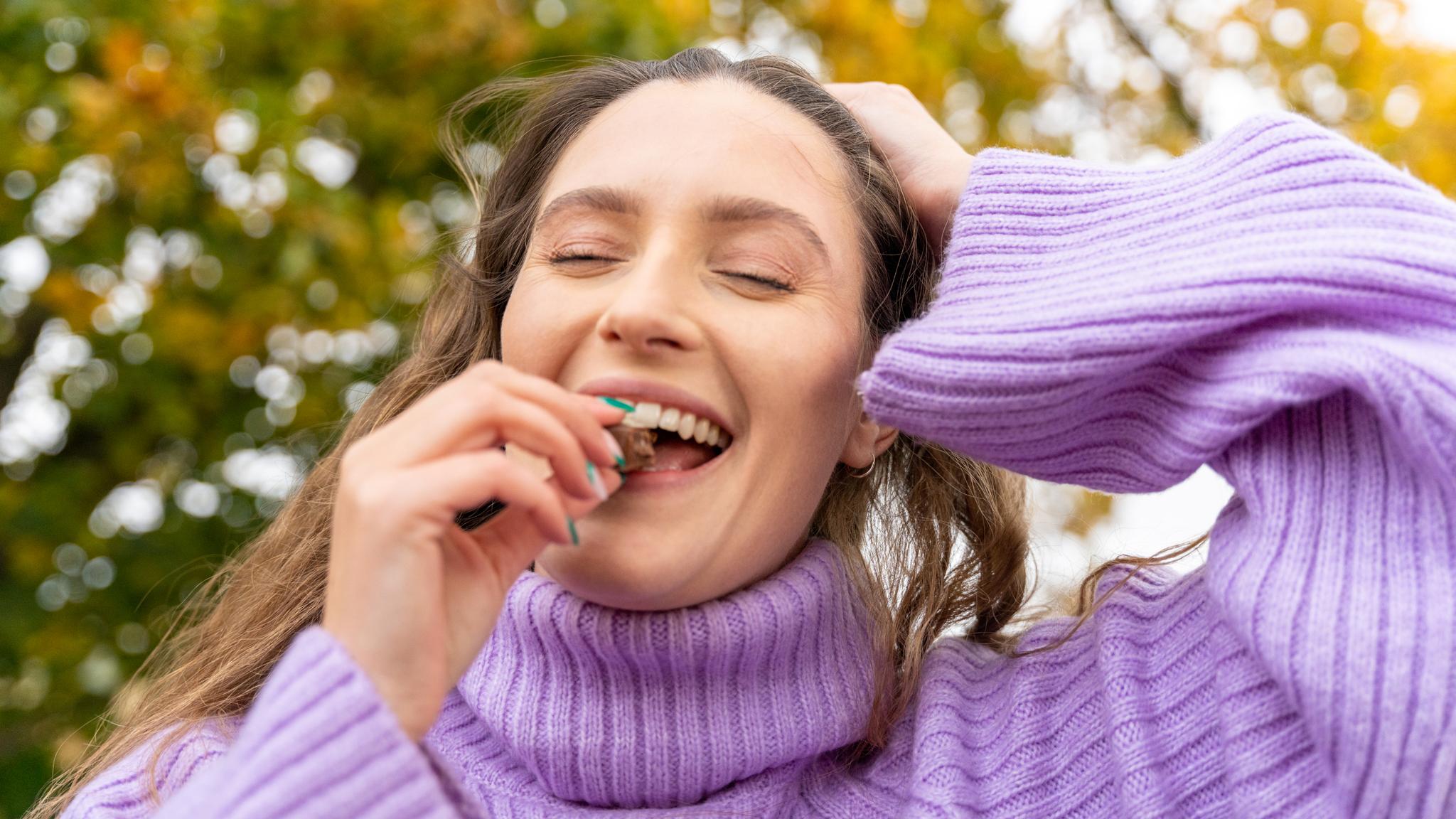 A woman eating a chocolate from the Kvarstad cafe and shop, Eastern Norway.