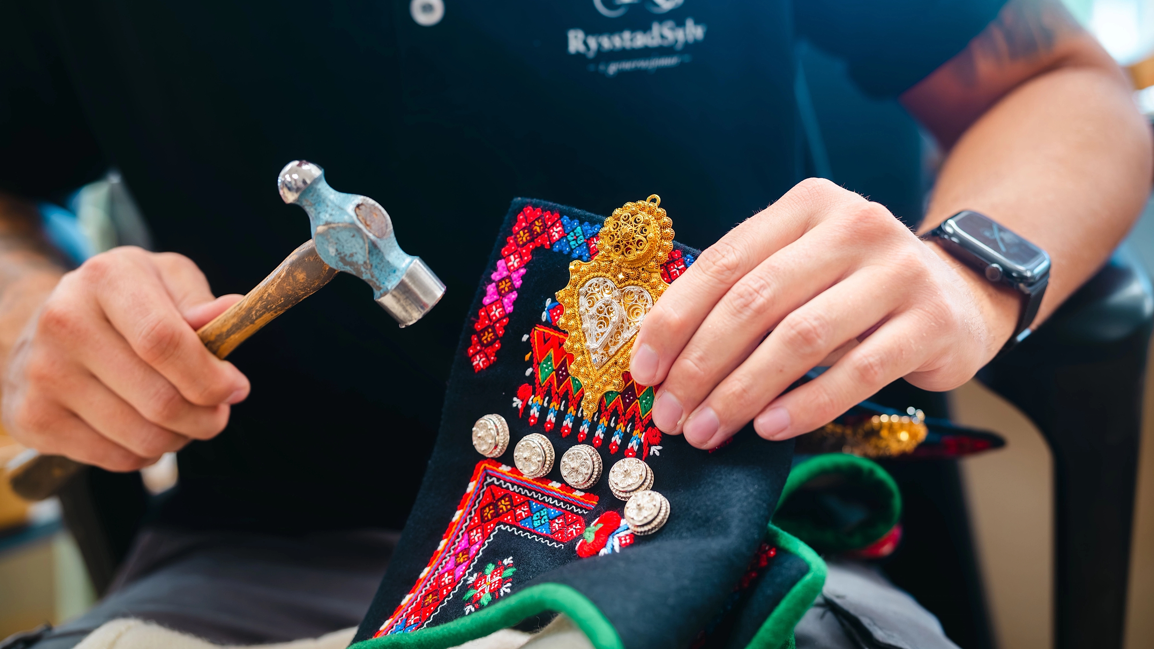 A silversmith hammering on a sølje (silver brooch)