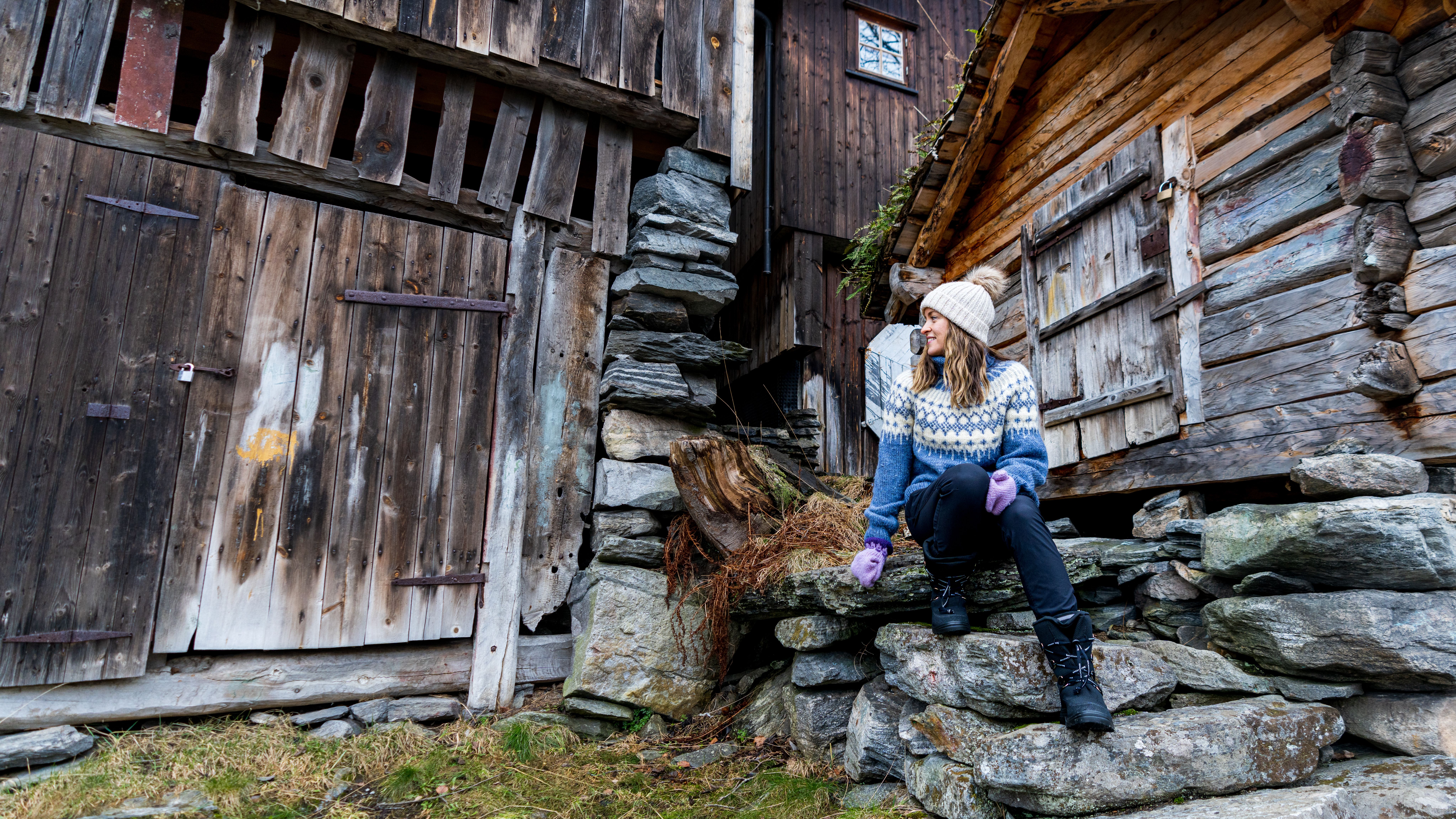 Woman in wool sweater sitting in old stairs in Geiranger