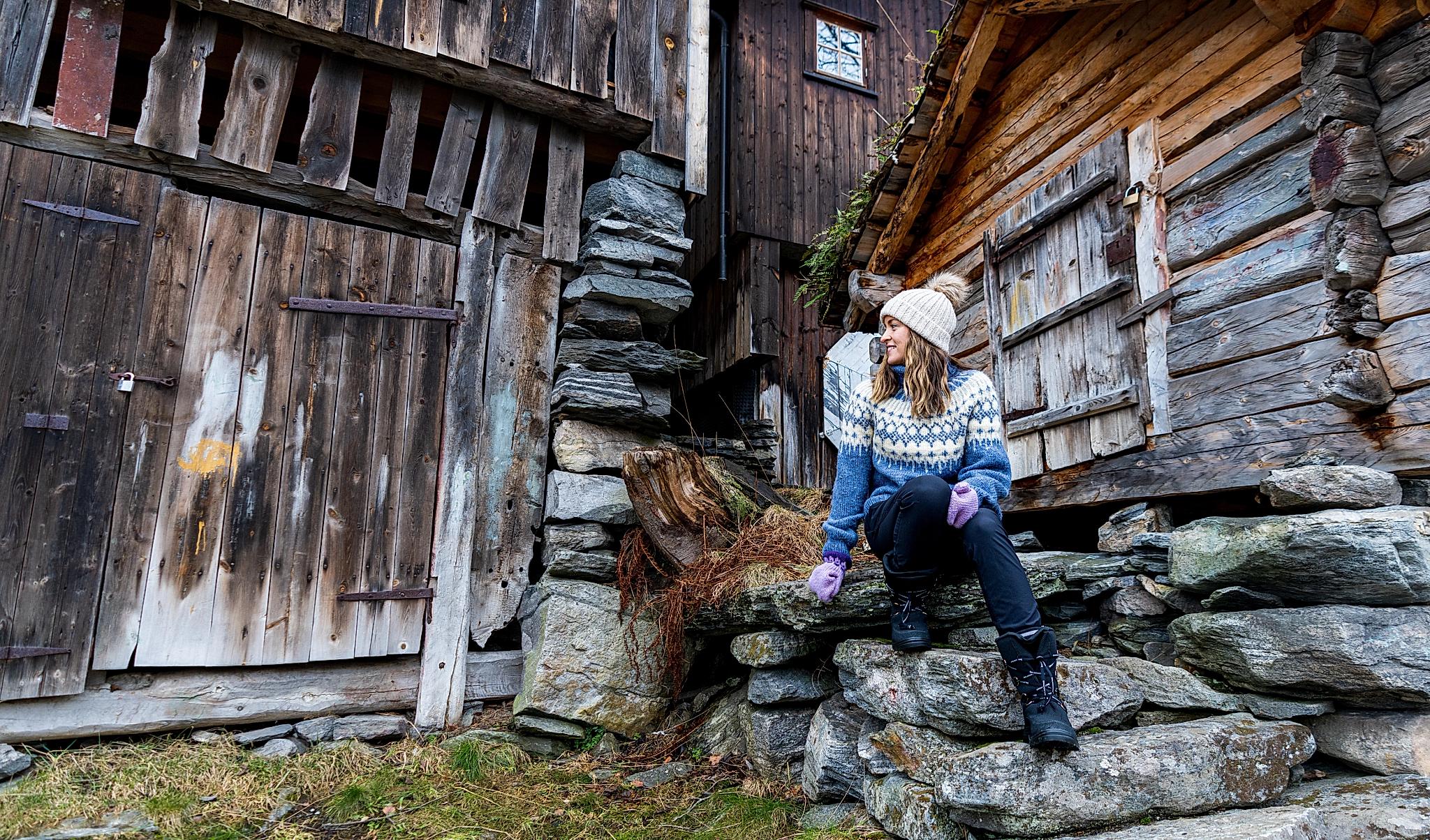 Woman in wool sweater sitting in old stairs in Geiranger
