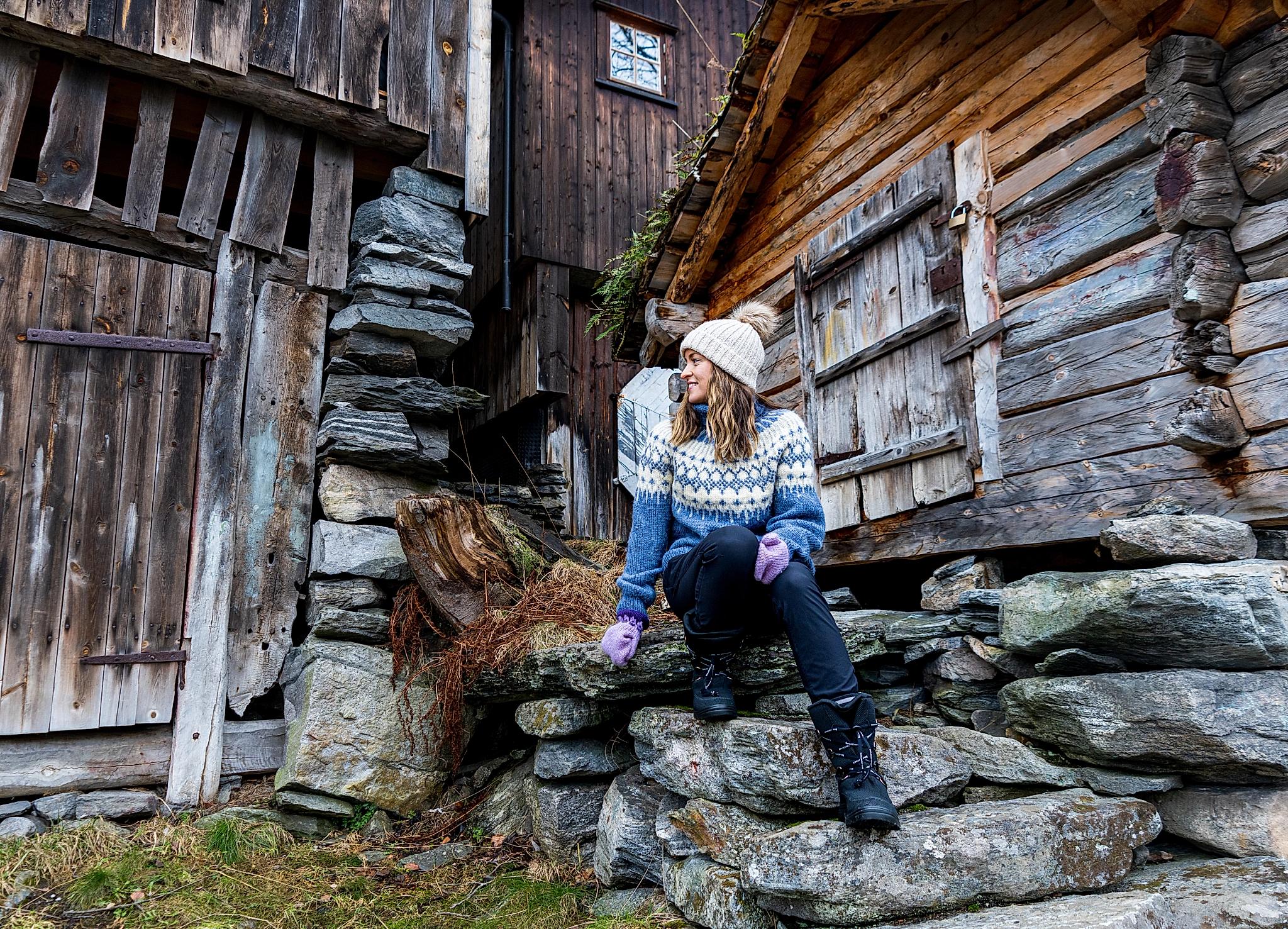 Woman in wool sweater sitting in old stairs in Geiranger