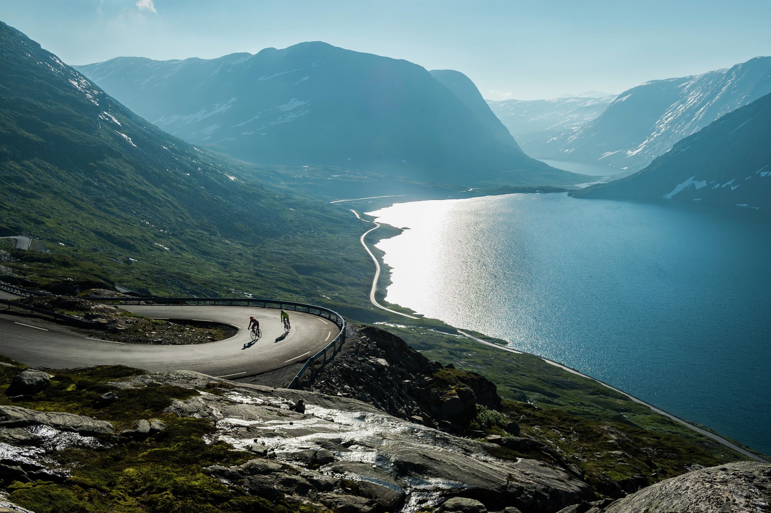 Two people road cycling up a winding road above the Geirangerfjord in Fjord Norway