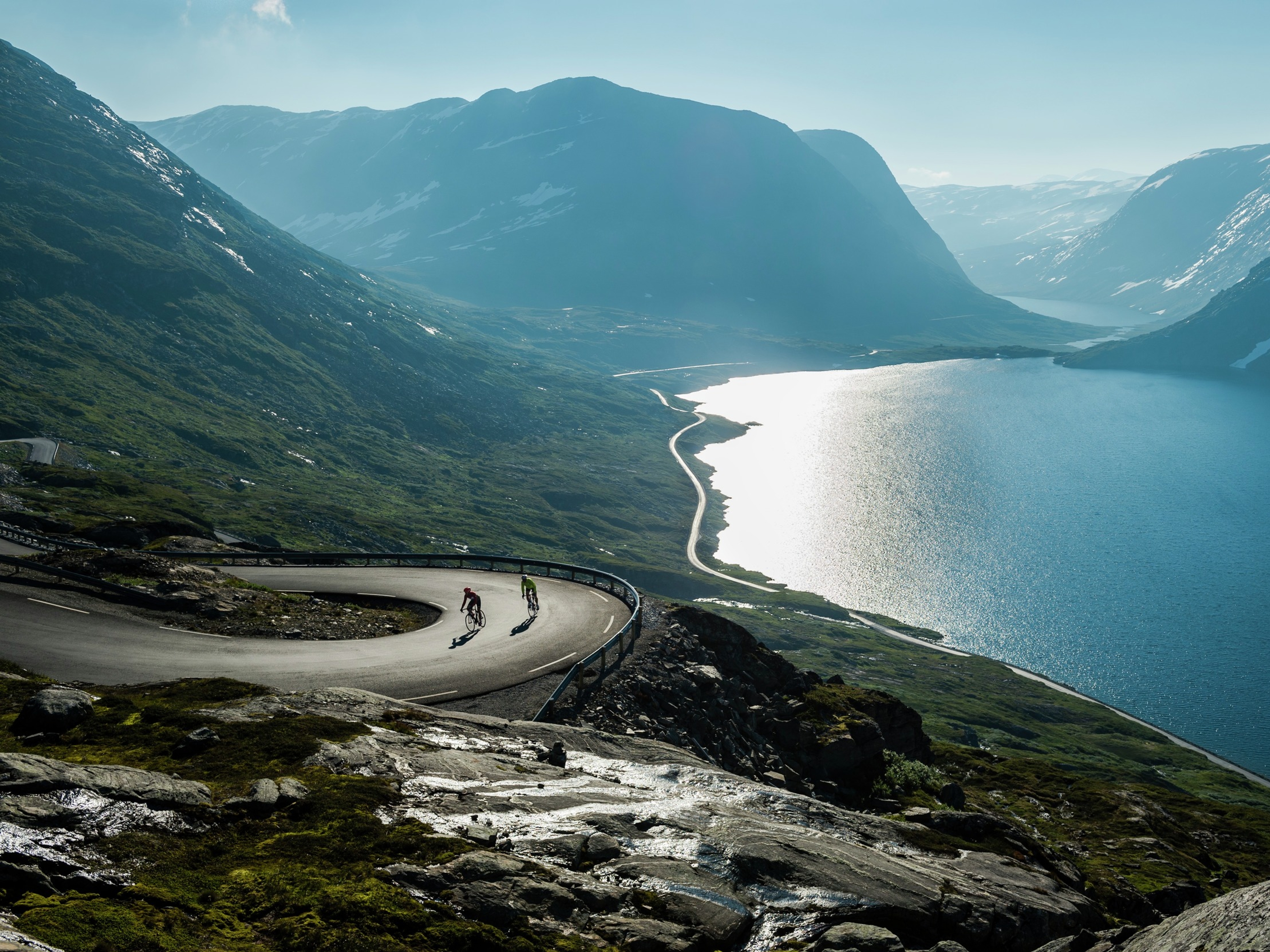 Two people road cycling up a winding road above the Geirangerfjord in Fjord Norway