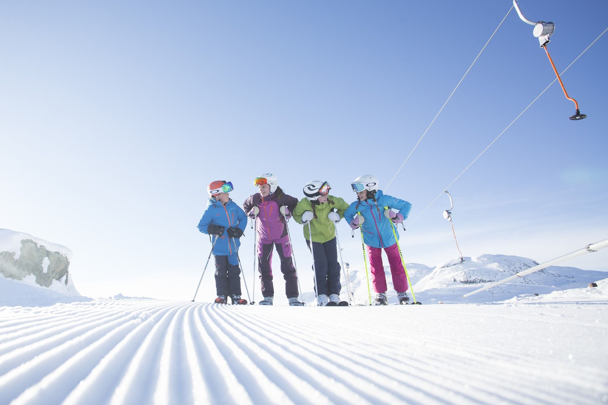 Four kids with skiers stand on a freshly groomed slope next to a button lift in Hemsedal, Eastern Norway
