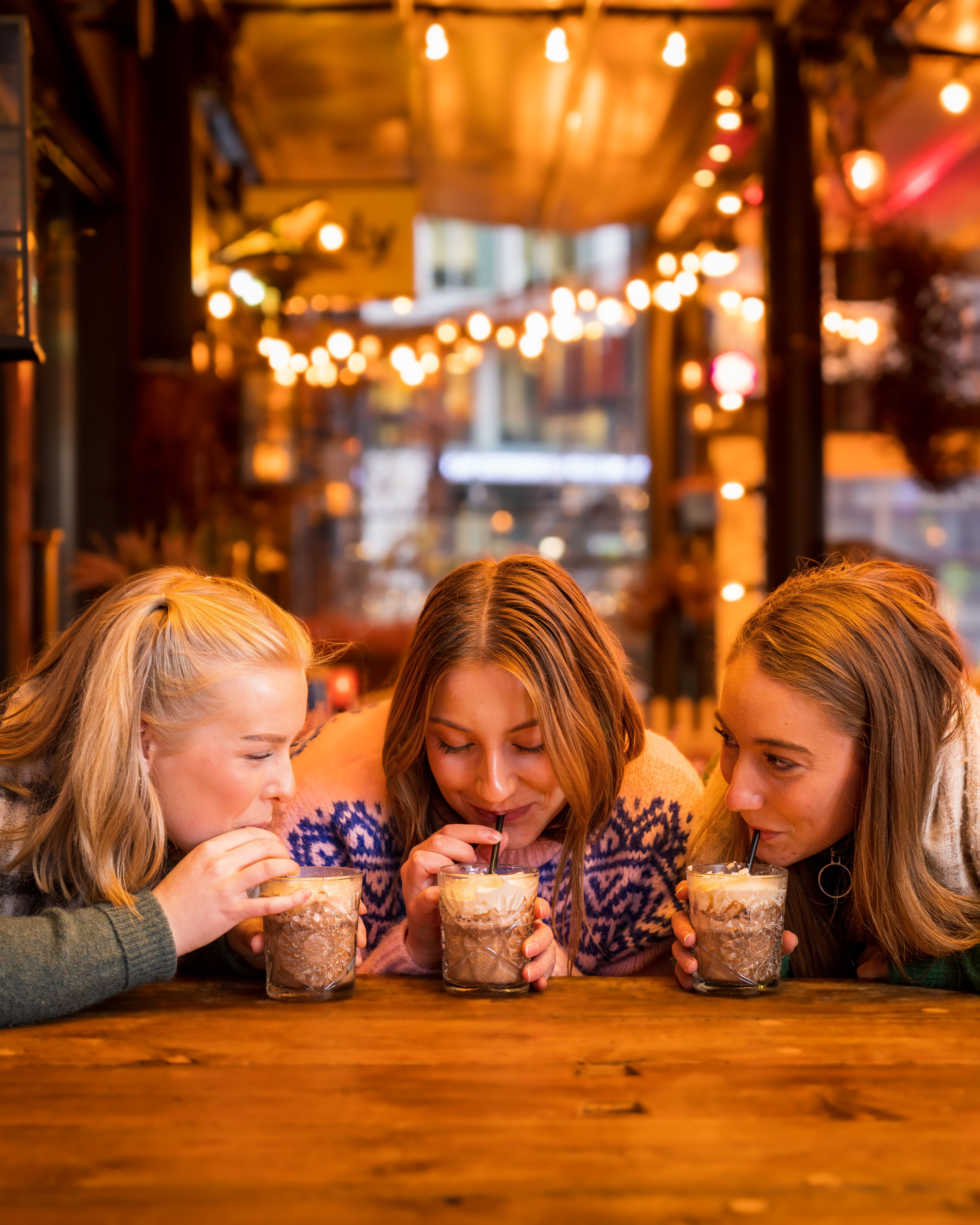 Three girls drinking hot chocolate at Aker Brygge in Oslo, Eastern Norway