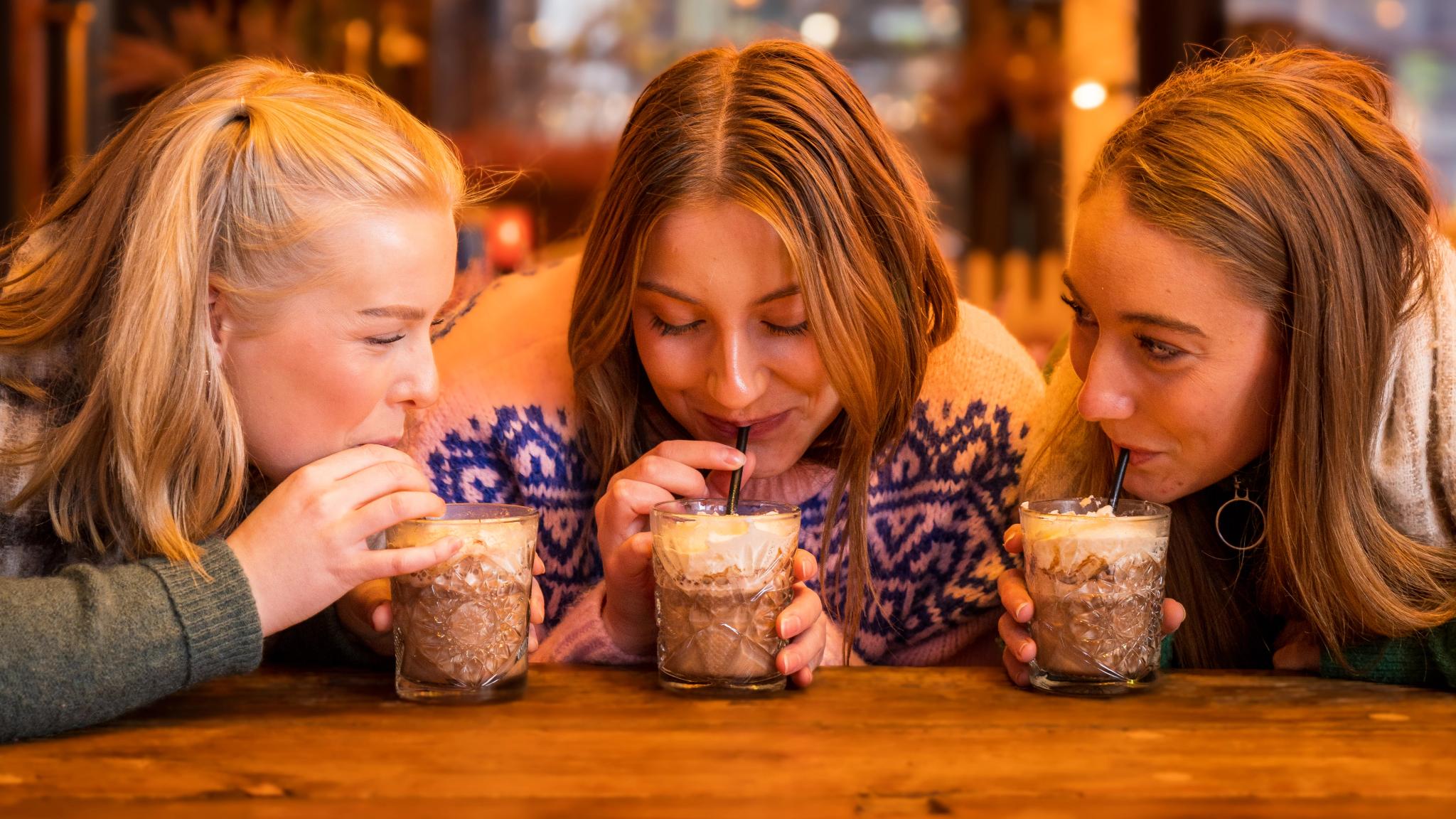 Three girls drinking hot chocolate at Aker Brygge in Oslo, Eastern Norway