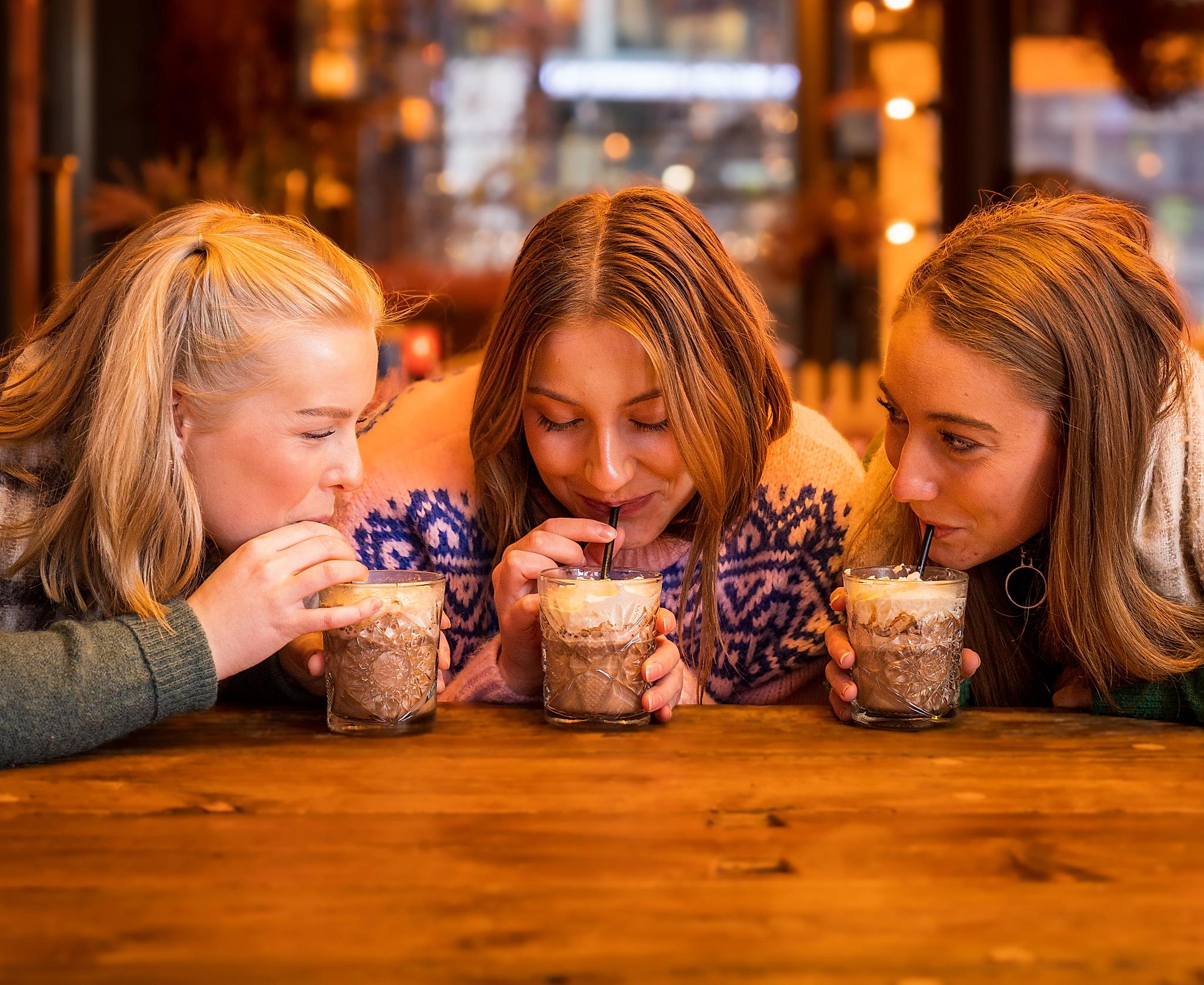 Three girls drinking hot chocolate at Aker Brygge in Oslo, Eastern Norway