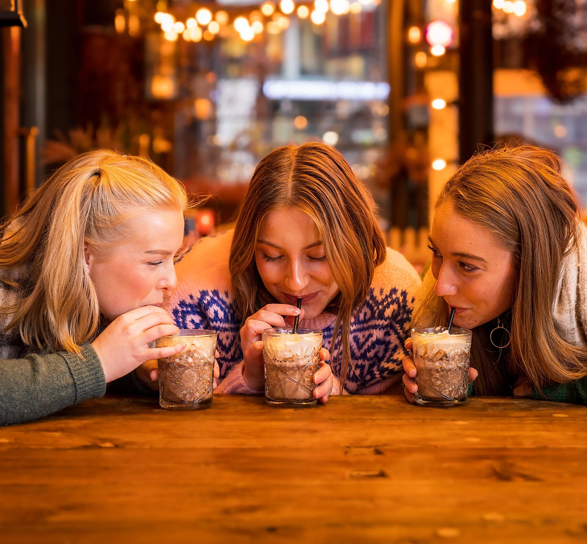 Three girls drinking hot chocolate at Aker Brygge in Oslo, Eastern Norway