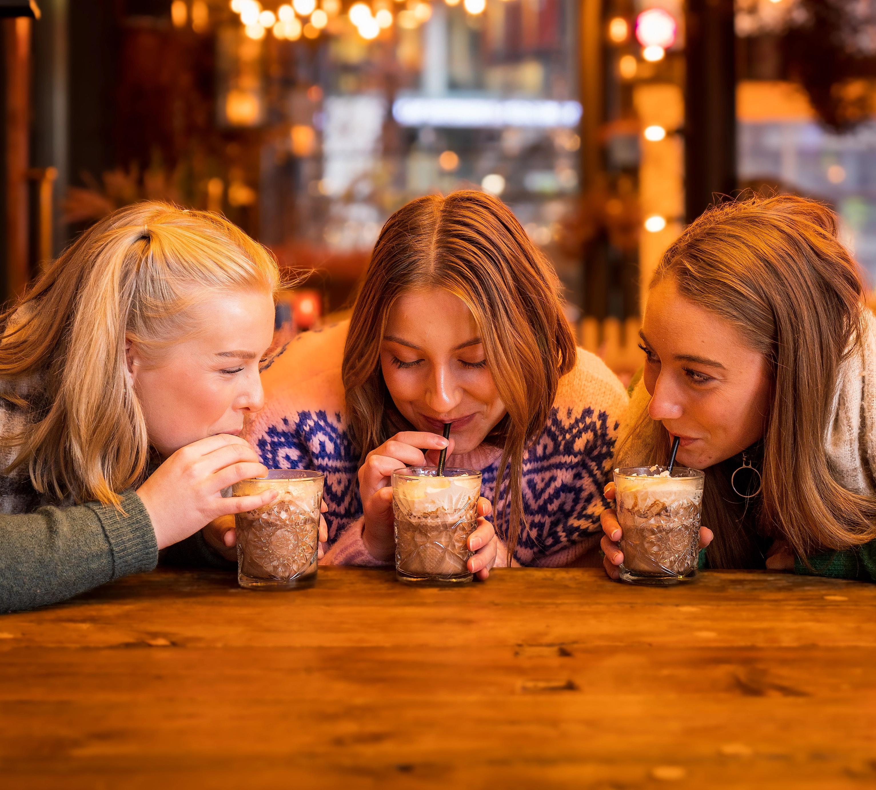 Three girls drinking hot chocolate at Aker Brygge in Oslo, Eastern Norway