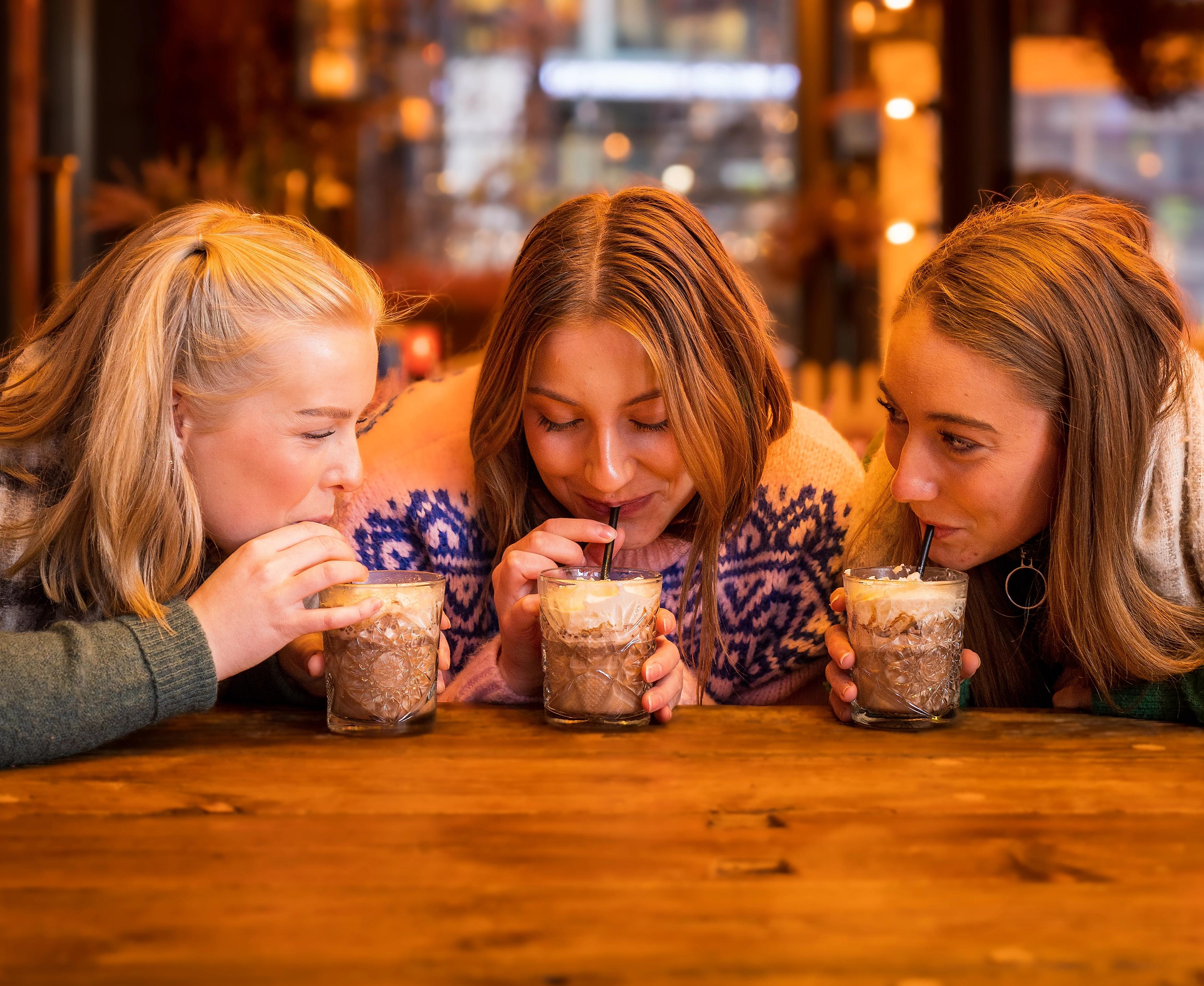 Three girls drinking hot chocolate at Aker Brygge in Oslo, Eastern Norway