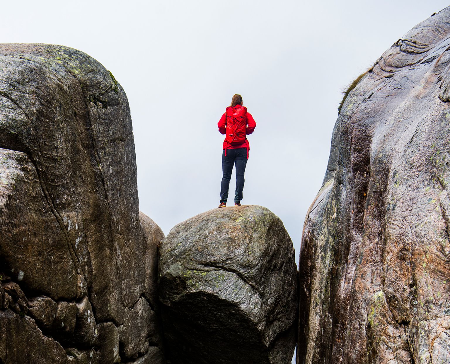 A woman standing on the famous Kjeragbolten rock on Mount Kjerag in Ryfylke, Fjord Norway