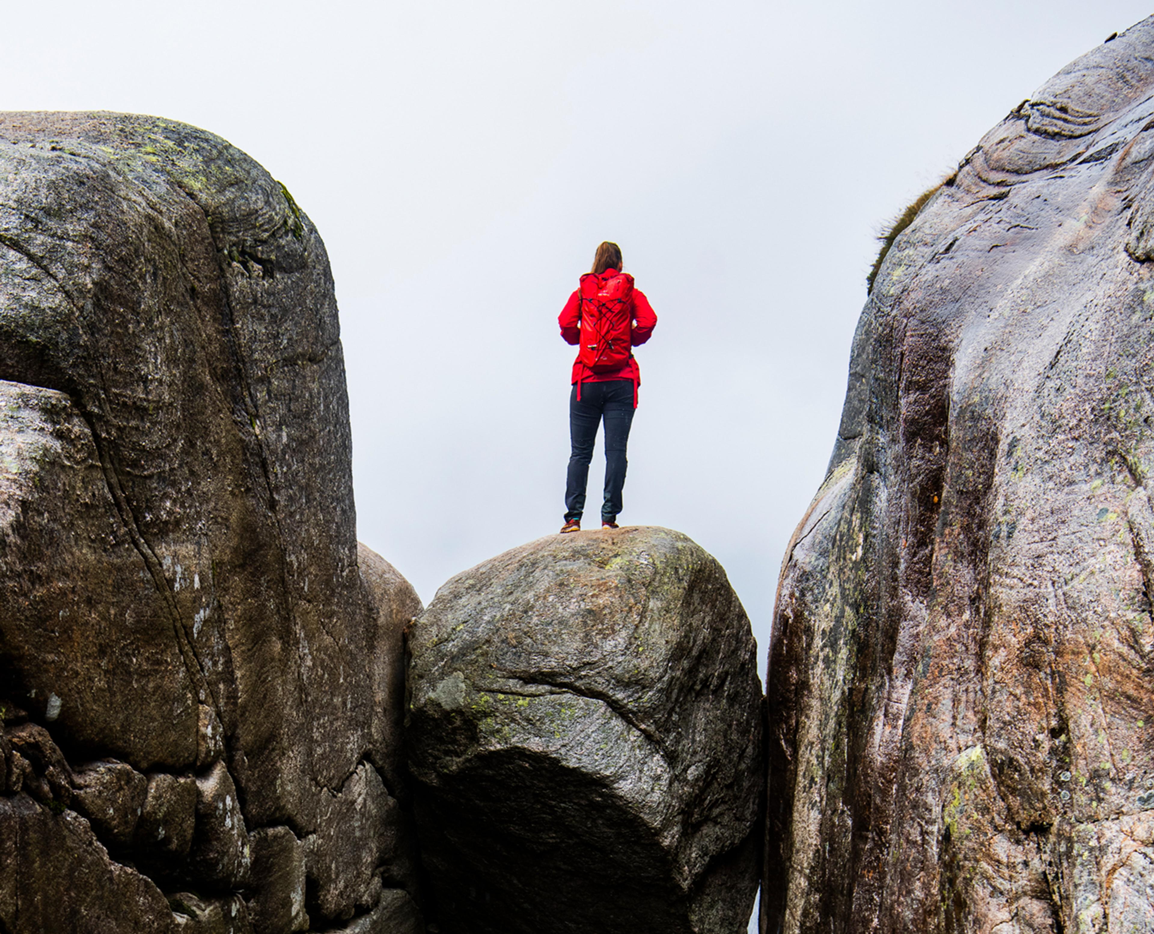 A woman standing on the famous Kjeragbolten rock on Mount Kjerag in Ryfylke, Fjord Norway