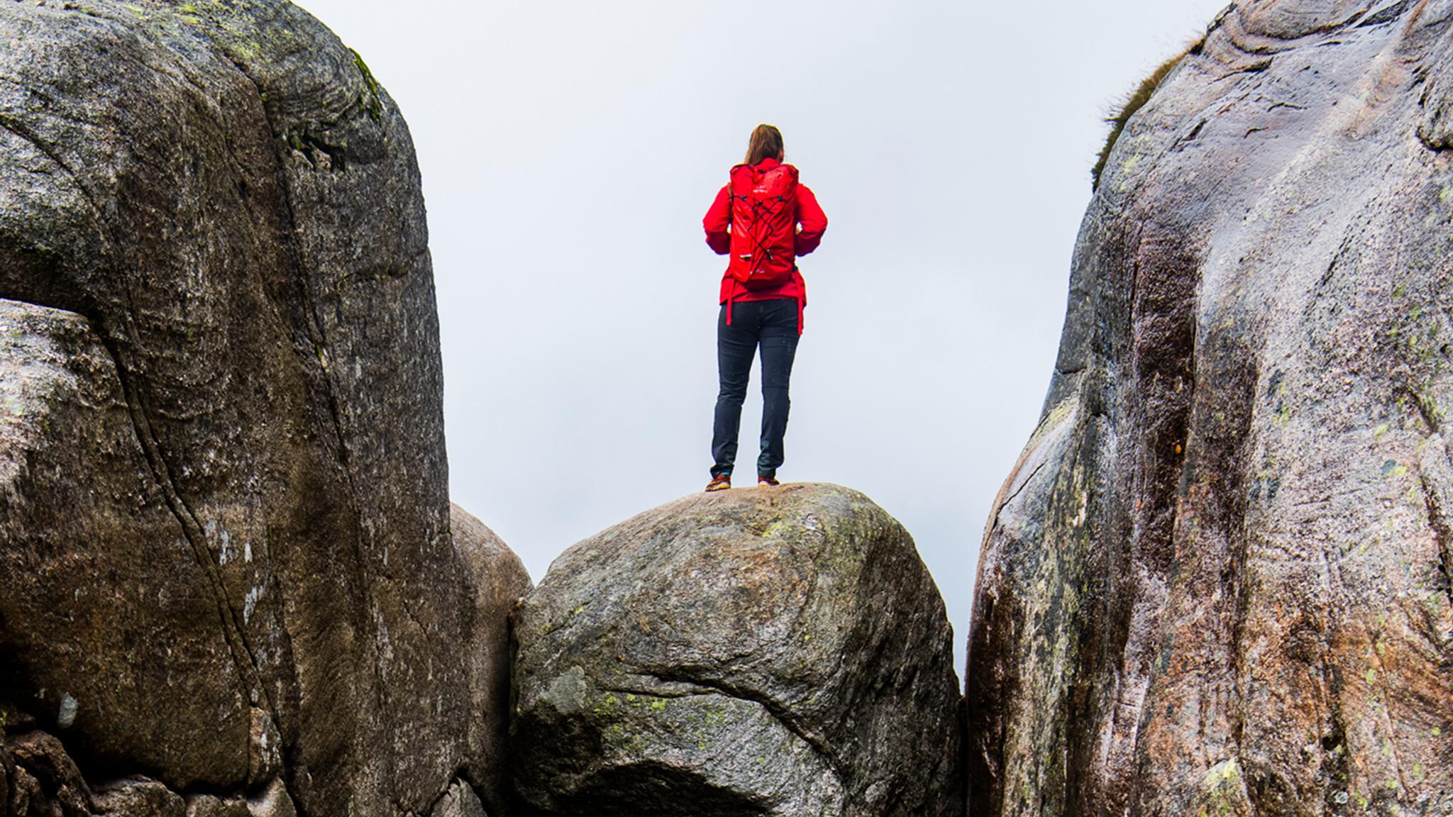 A woman standing on the famous Kjeragbolten rock on Mount Kjerag in Ryfylke, Fjord Norway