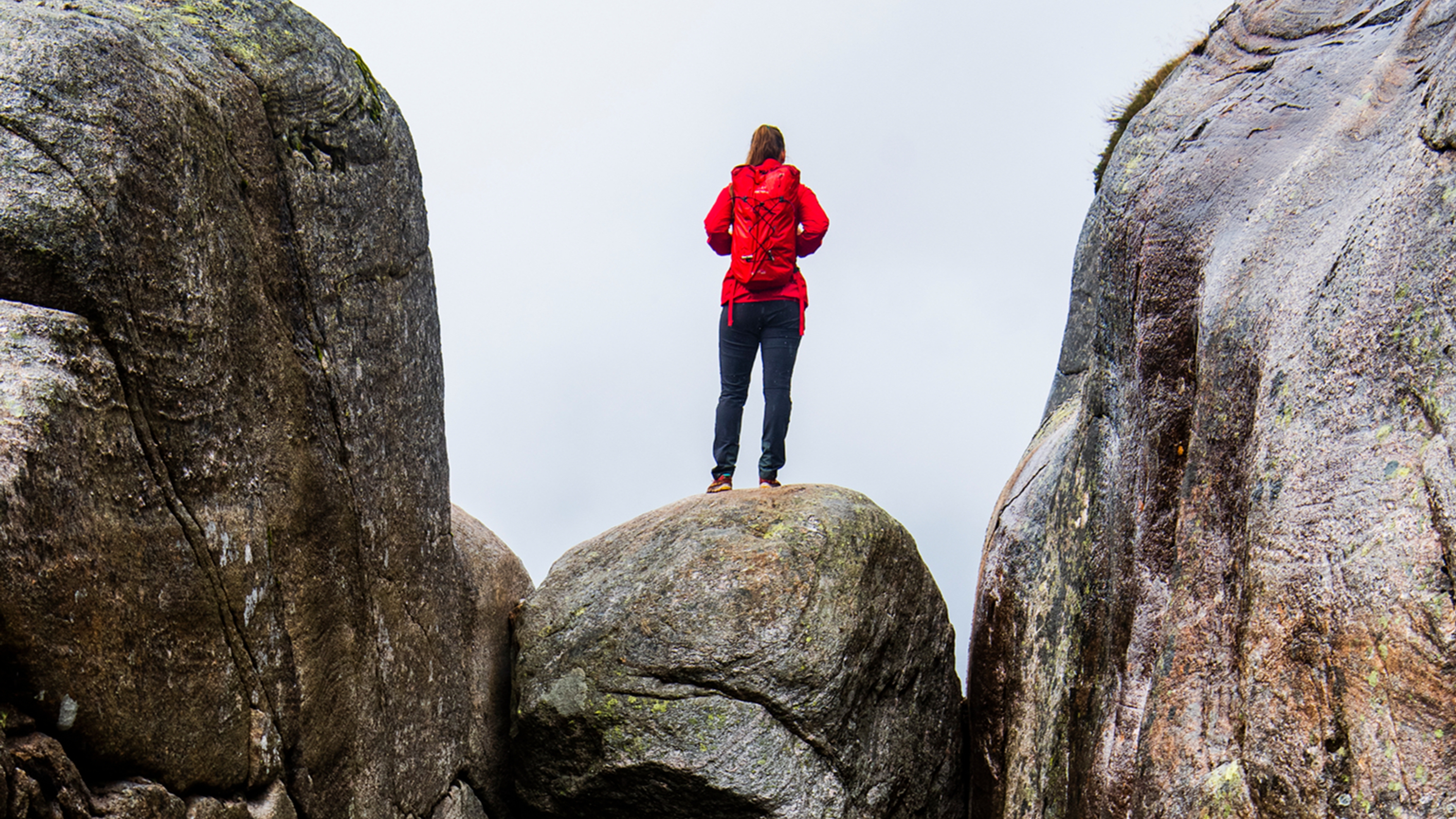 A woman standing on the famous Kjeragbolten rock on Mount Kjerag in Ryfylke, Fjord Norway