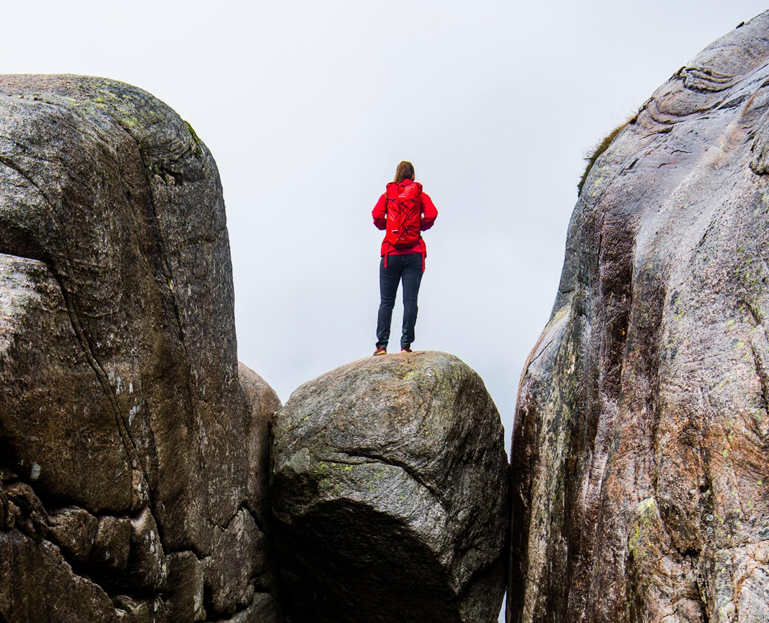 A woman standing on the famous Kjeragbolten rock on Mount Kjerag in Ryfylke, Fjord Norway