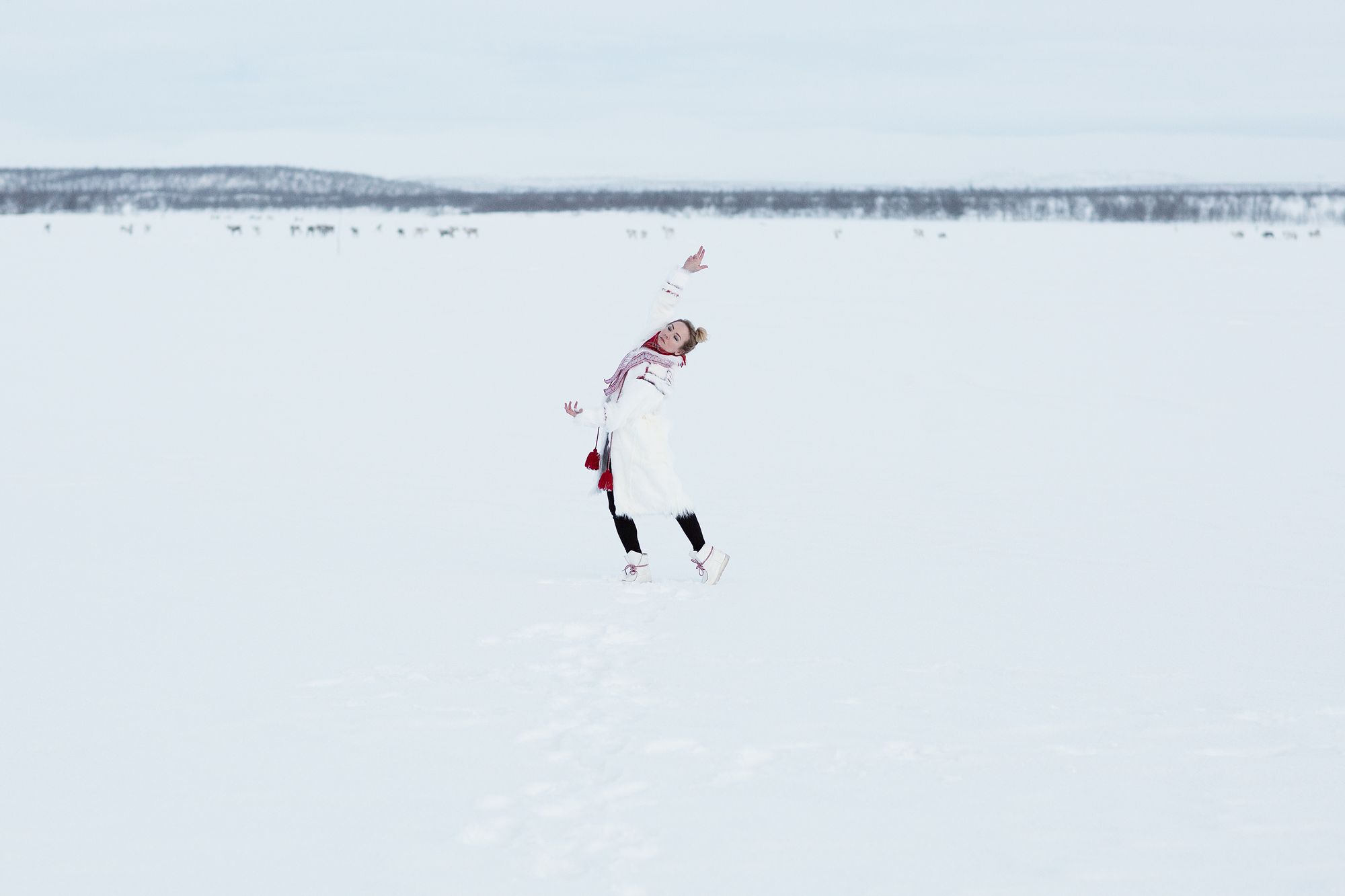 Elle Márjá Eira dancing in the snow wearing sami-inspired clothes.