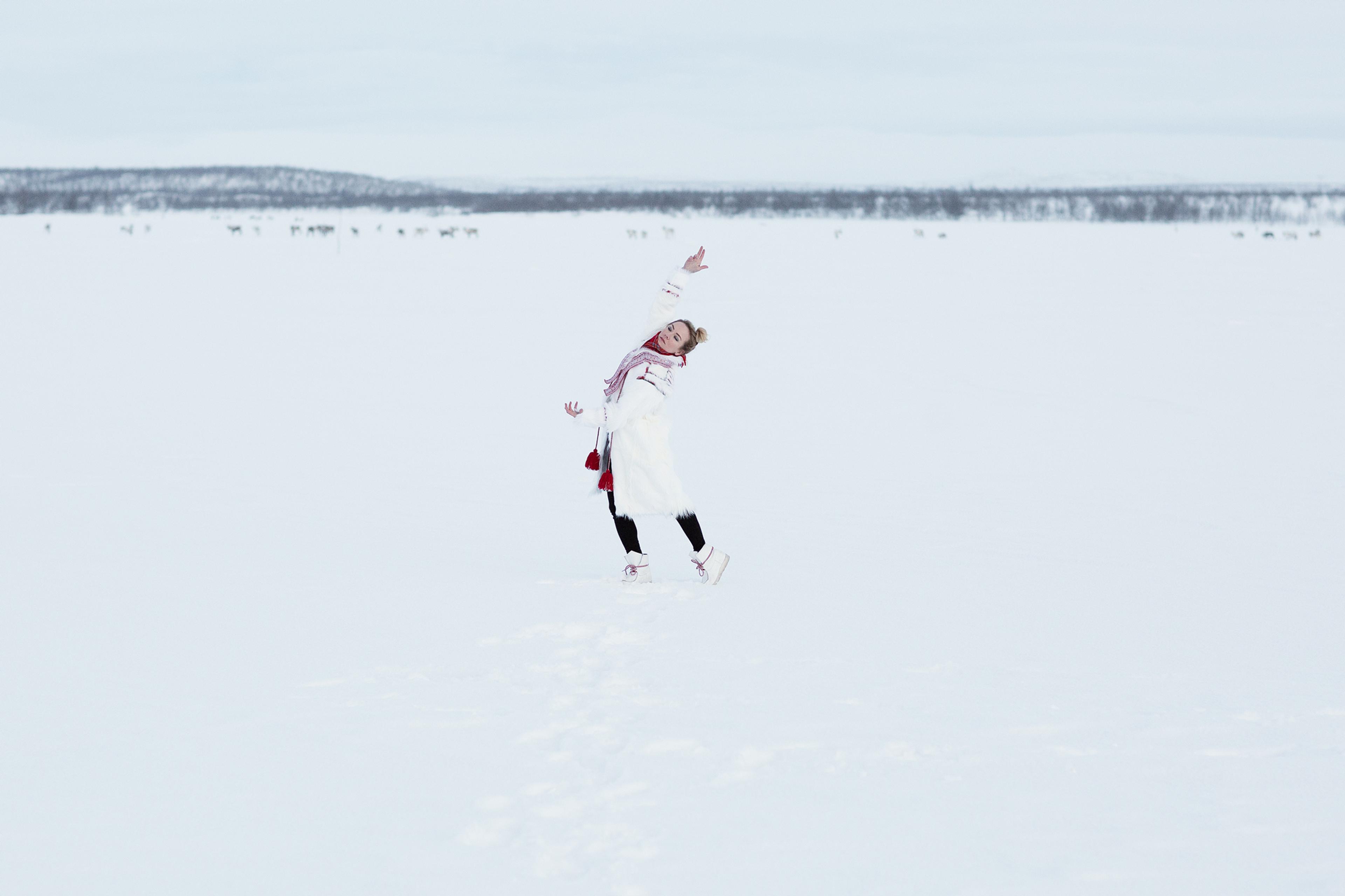Elle Márjá Eira dancing in the snow wearing sami-inspired clothes.