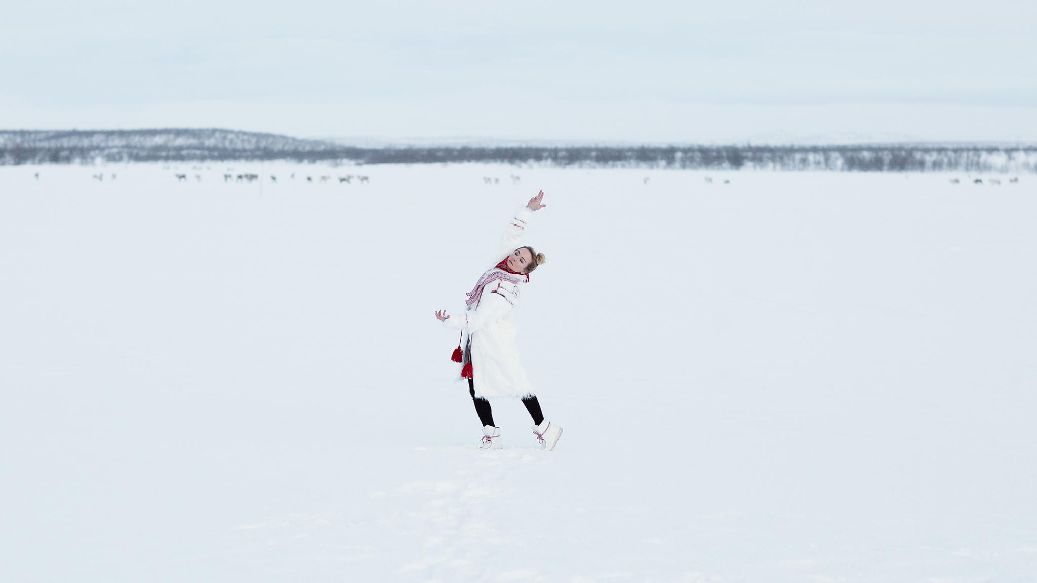Elle Márjá Eira dancing in the snow wearing sami-inspired clothes.
