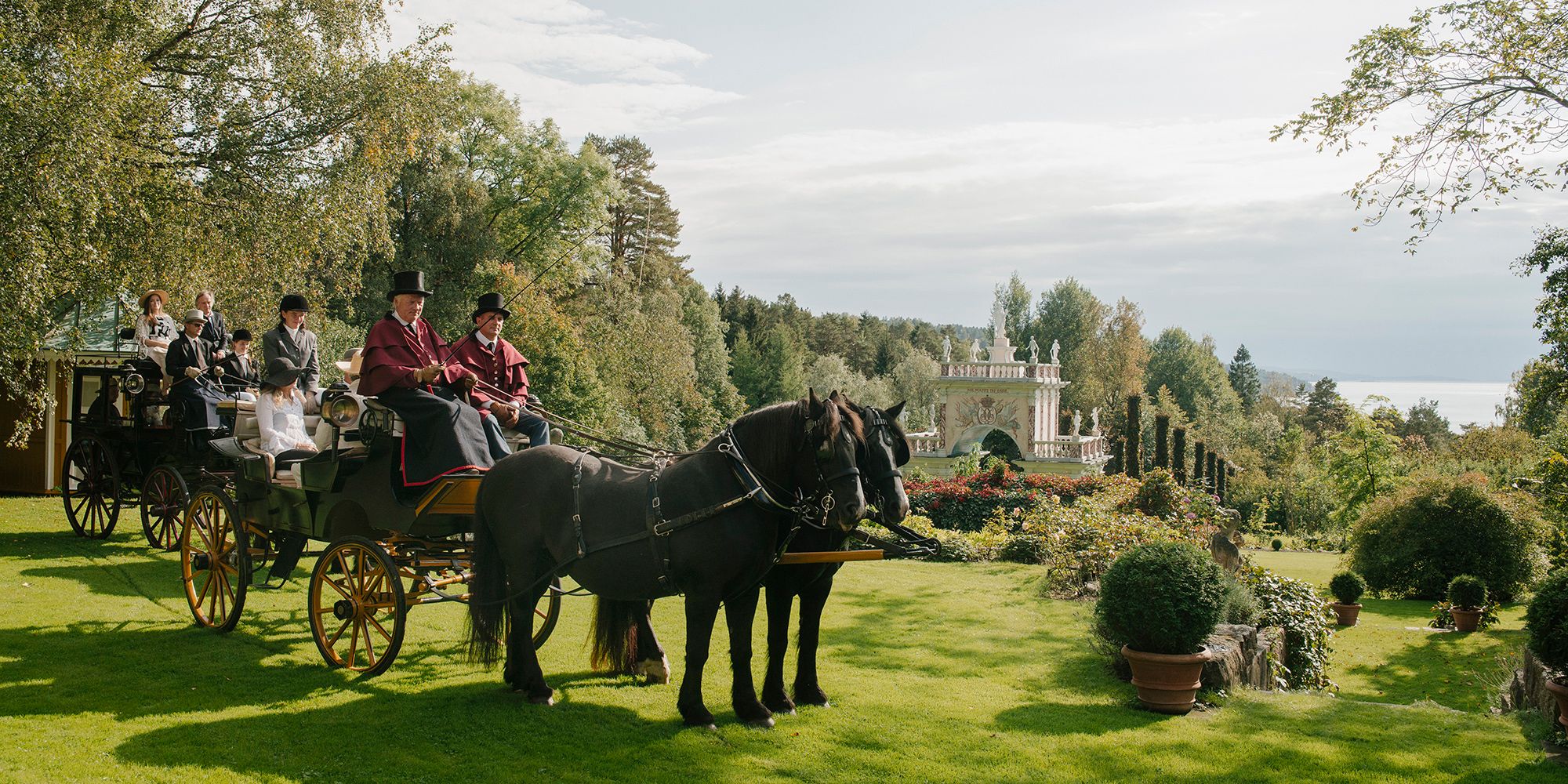 Mensen in een paardenkoets in het Havlystparken-park in de cultuurbestemming Ramme Gård in Hvitsten aan het Oslofjord in Oost-Noorwegen