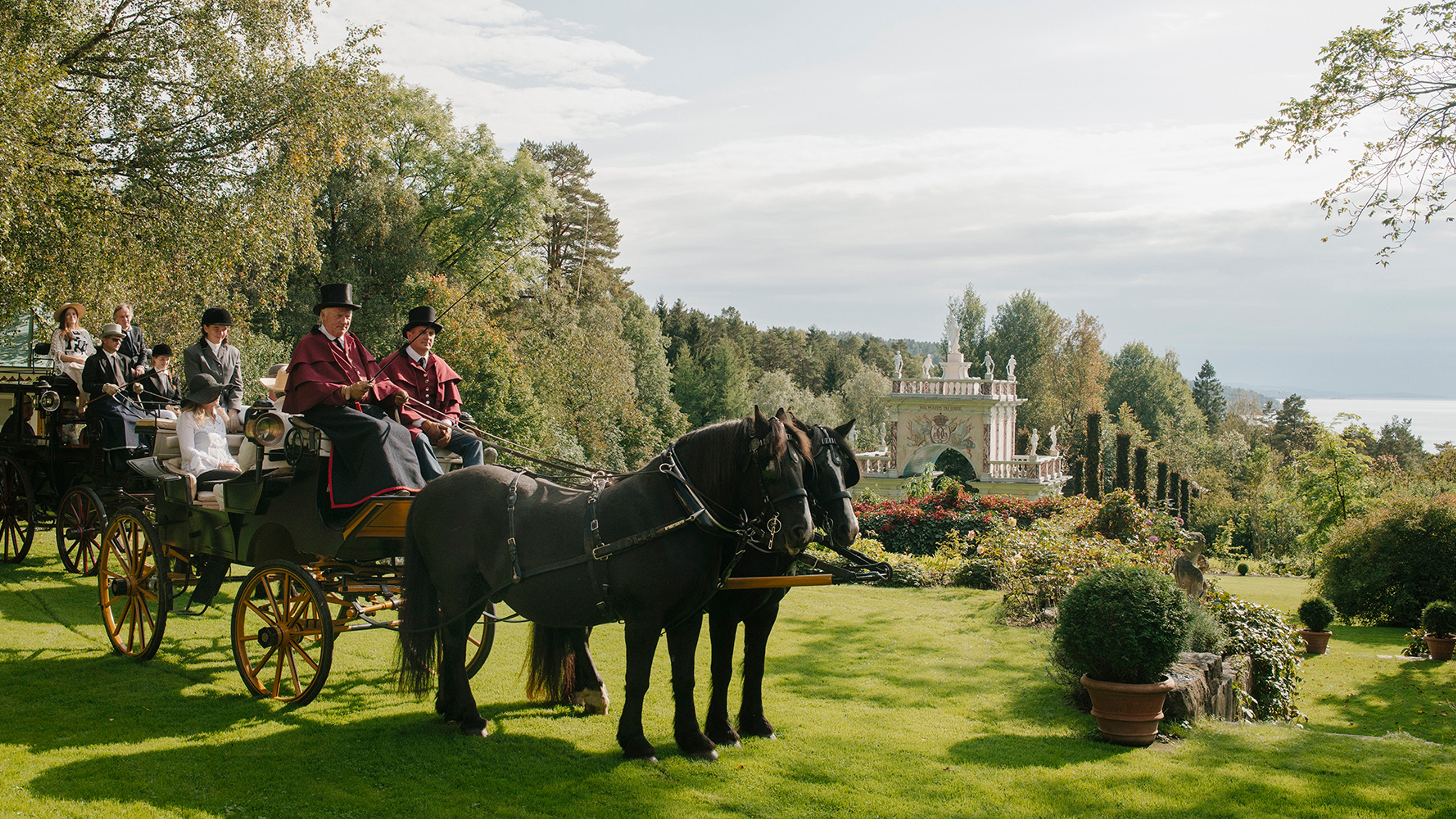People in a horse-drawn carriage in Havlystparken at the culture destination Ramme Gård in Hvitsten by the Oslofjord in Eastern Norway