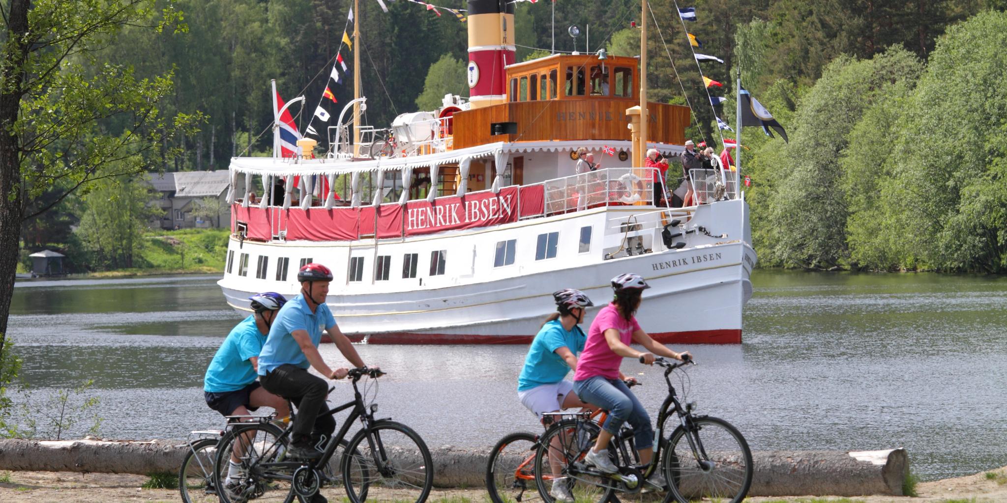 Cyklister passerar en kanalbåt på den nationella cykelvägen längs Telemarkskanalen i Østlandet.