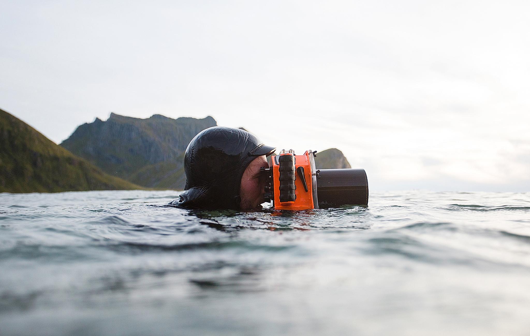 Hallvard Kolltveit, a surfer, swimming in the sea with a waterproof camera in Norway