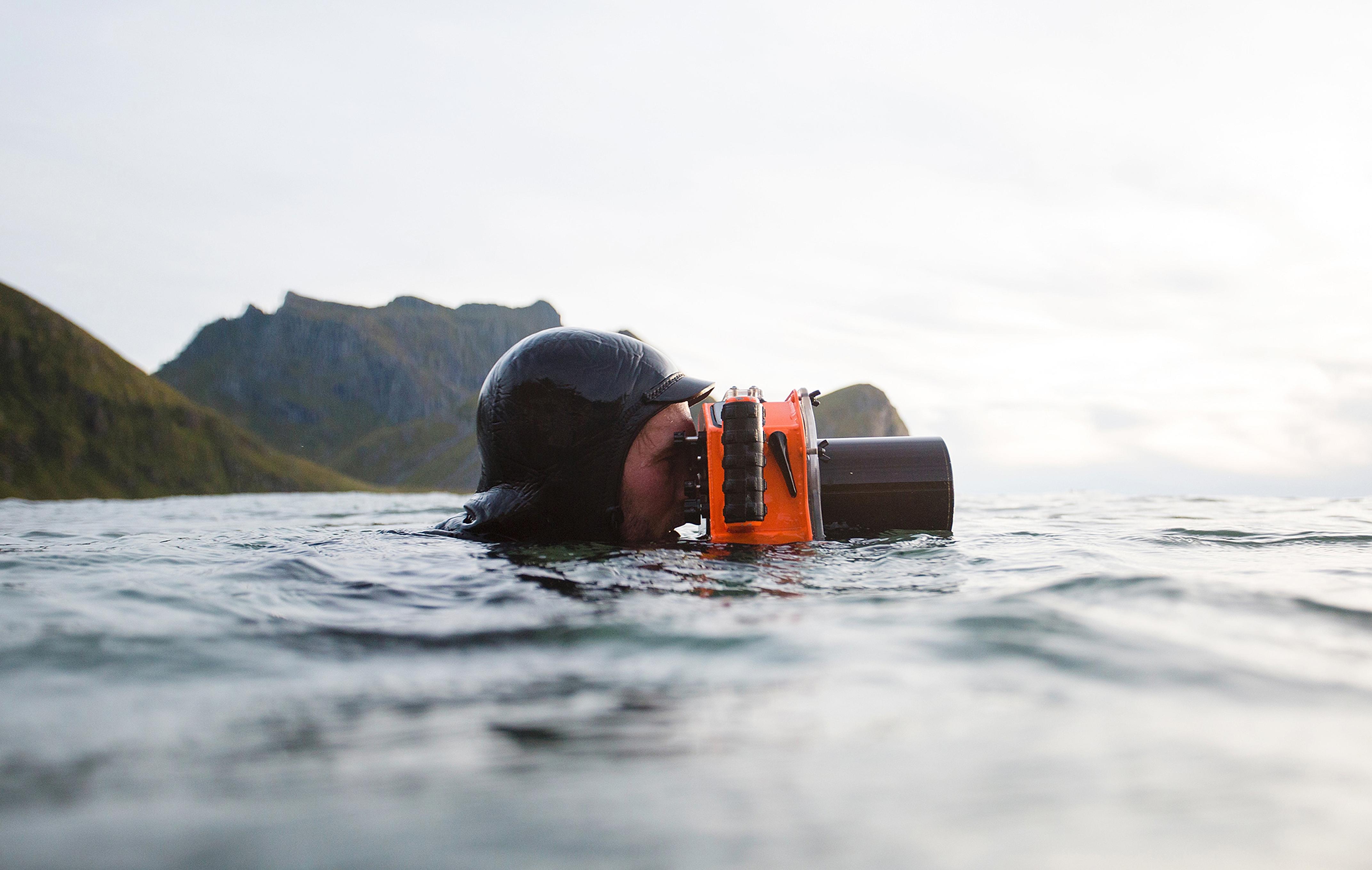 Hallvard Kolltveit, a surfer, swimming in the sea with a waterproof camera in Norway