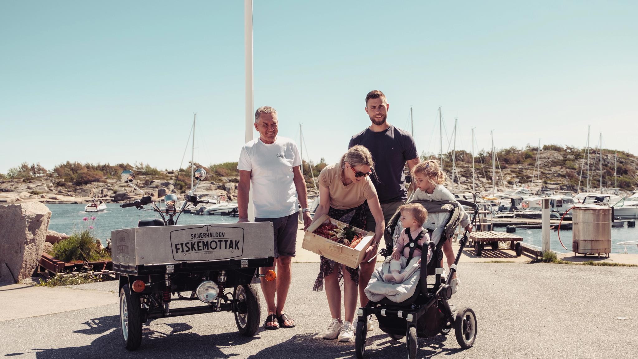 En familie kjøper en skalldyrkasse på Skjærhalden fiskemottak på Hvaler på Østlandet