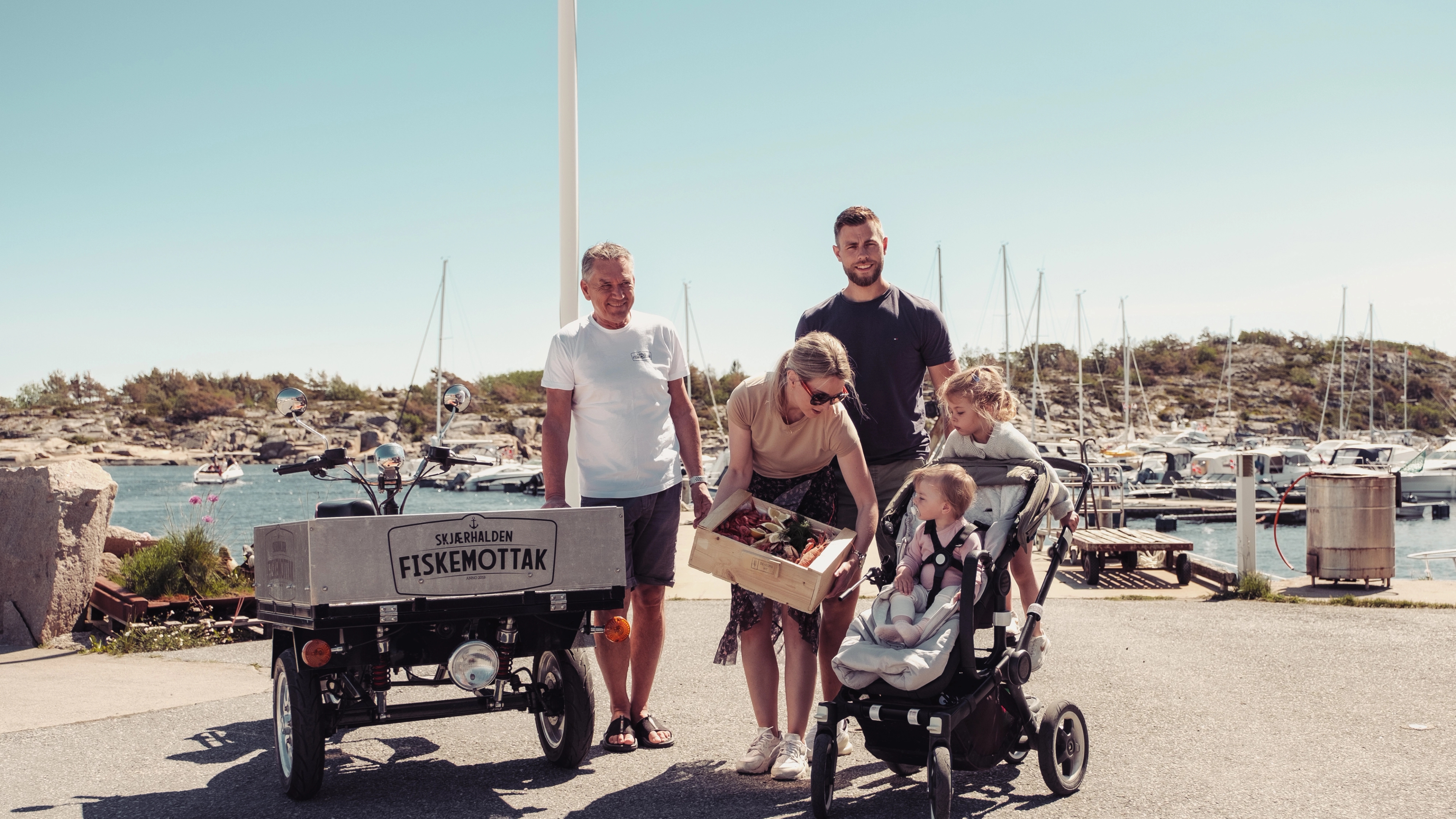 En familie kjøper en skalldyrkasse på Skjærhalden fiskemottak på Hvaler på Østlandet