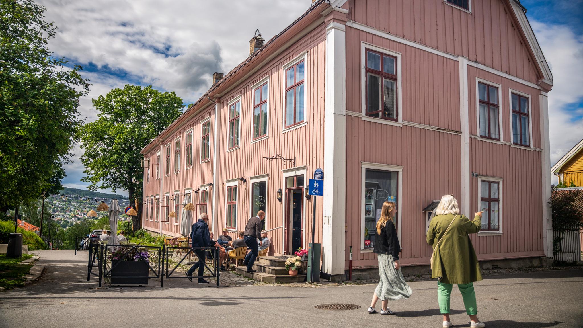 People exploring the old town of Kongsvinger next to a pink house