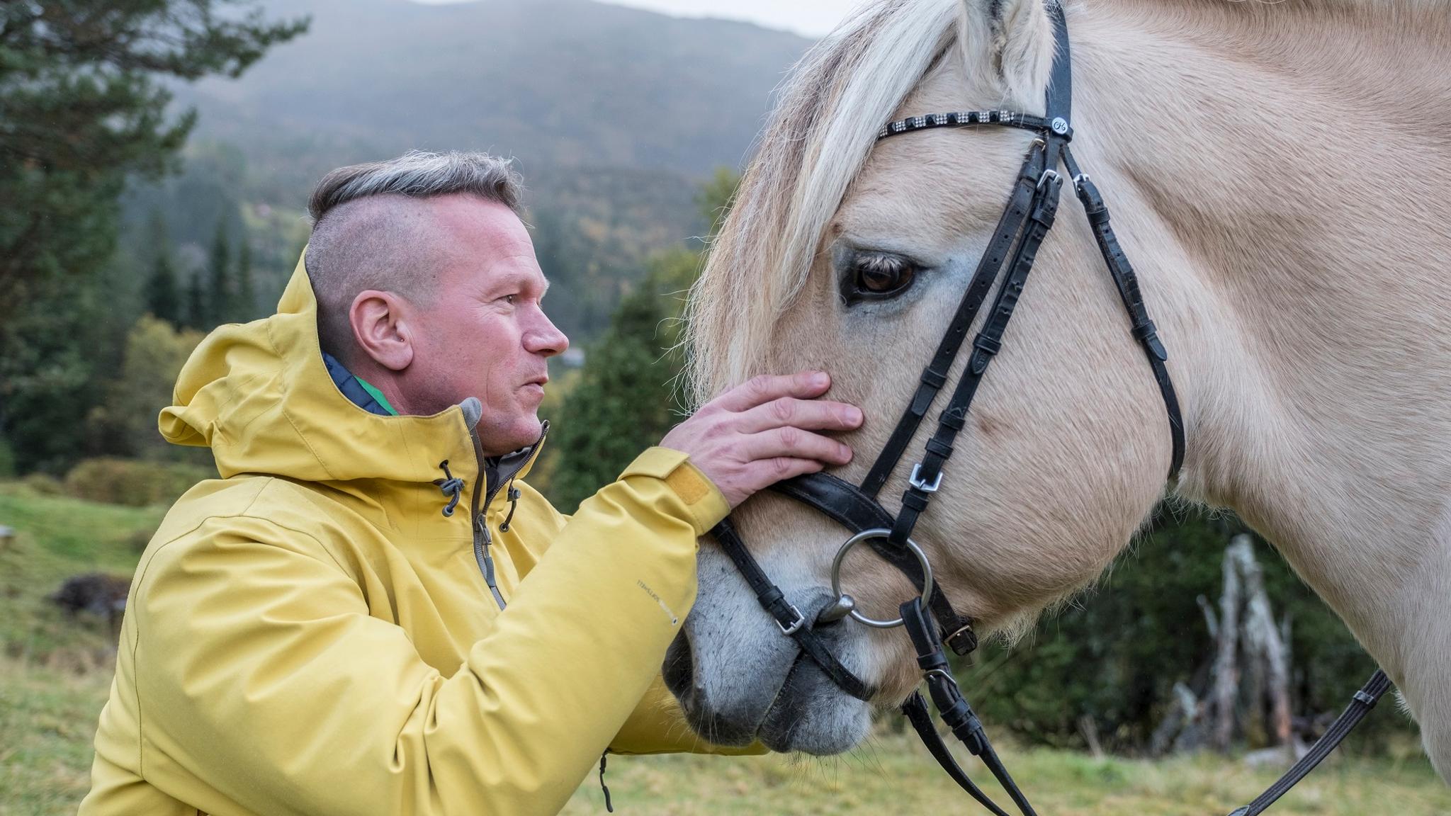 A man petting a fjord horse in Norway
