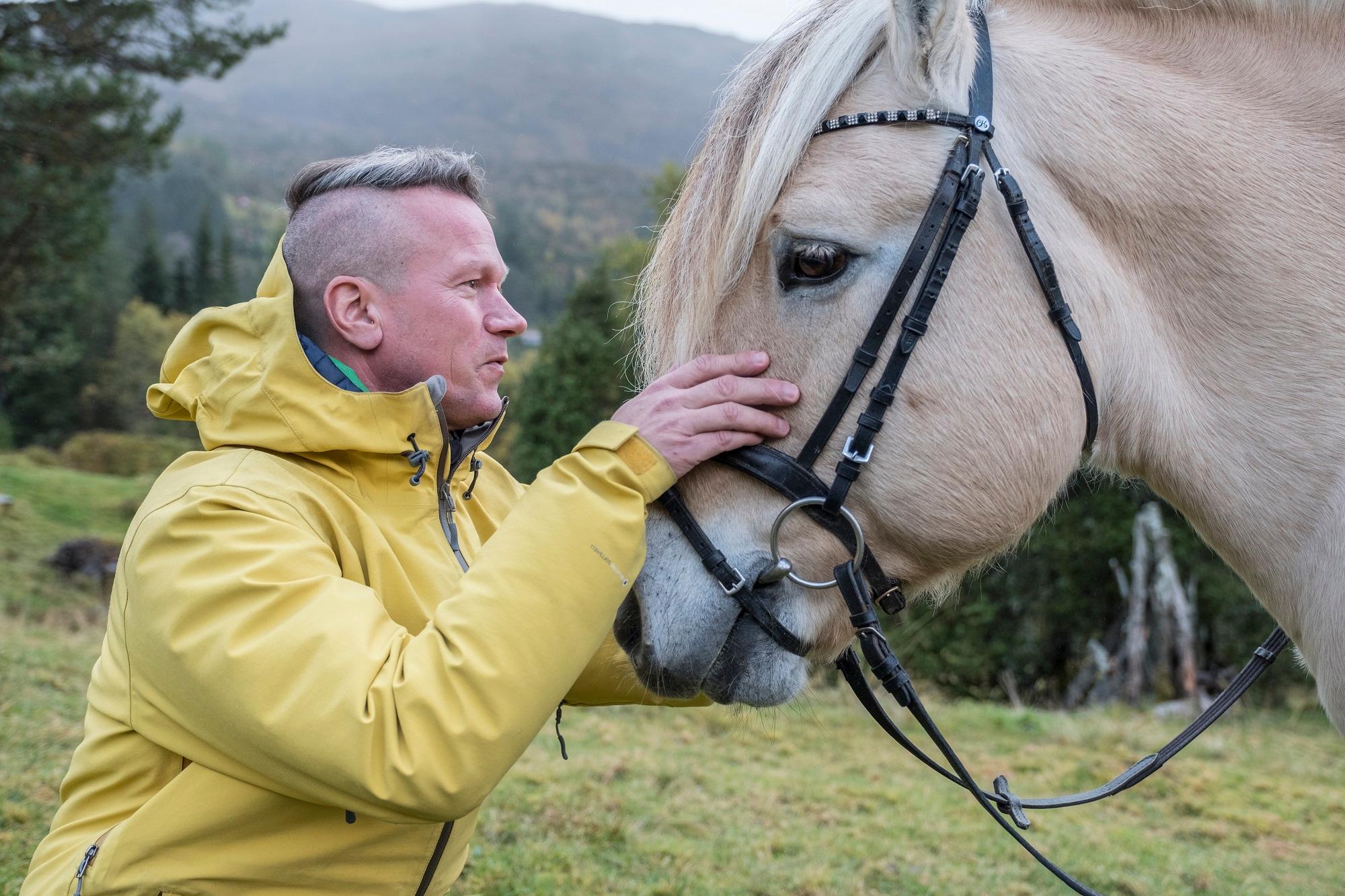 A man petting a fjord horse in Norway