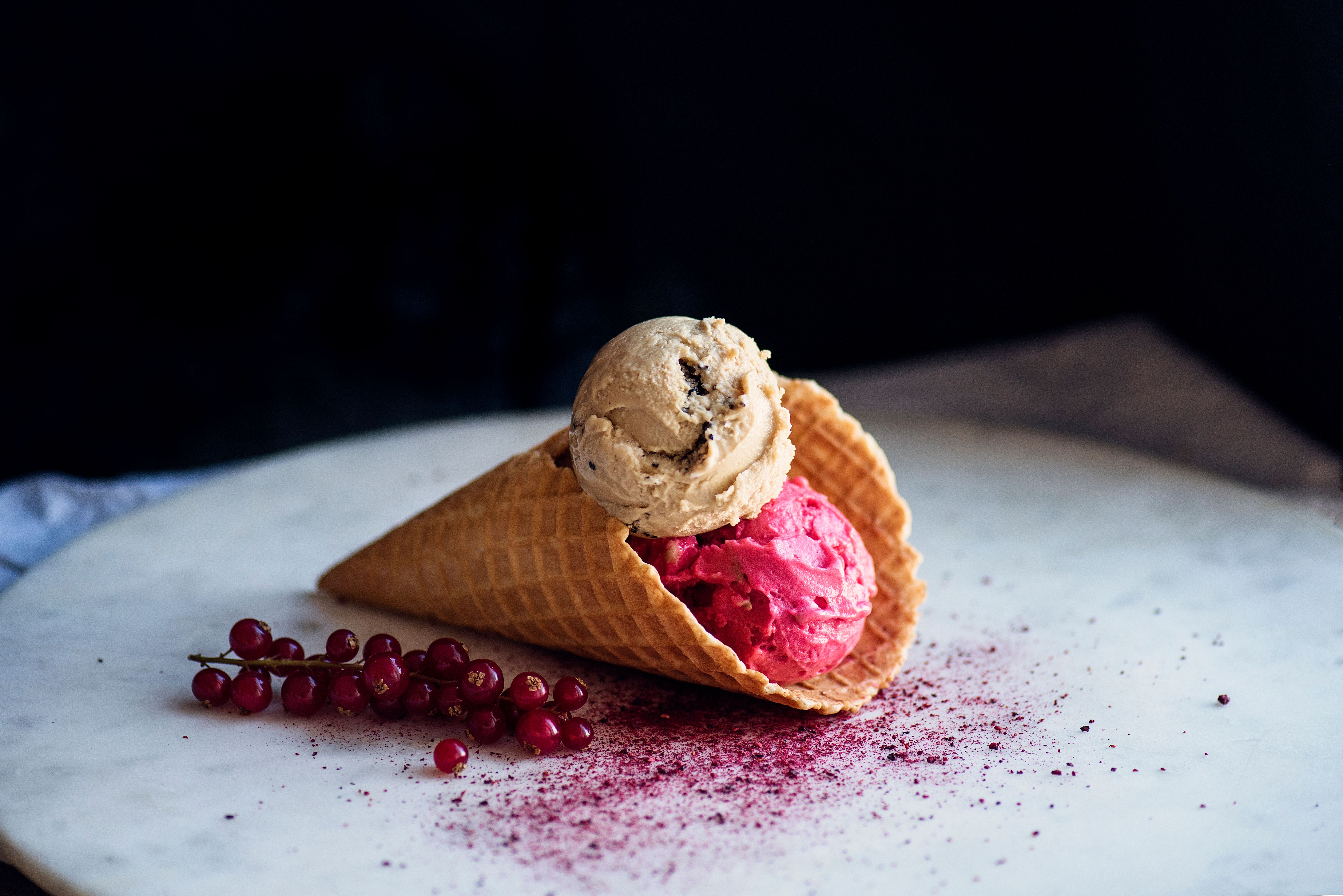 Ice-cream in a cone next to some red currants