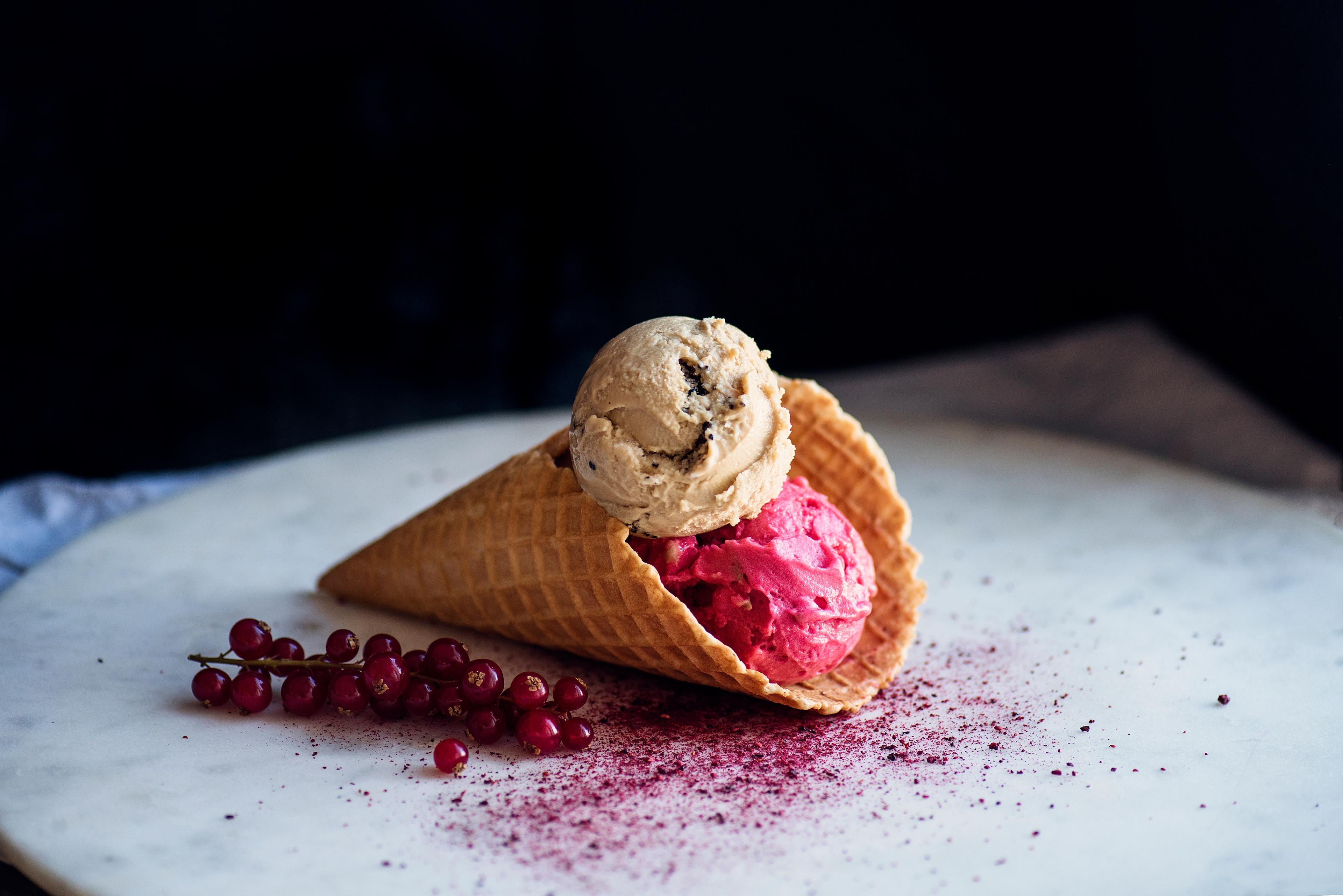 Ice-cream in a cone next to some red currants